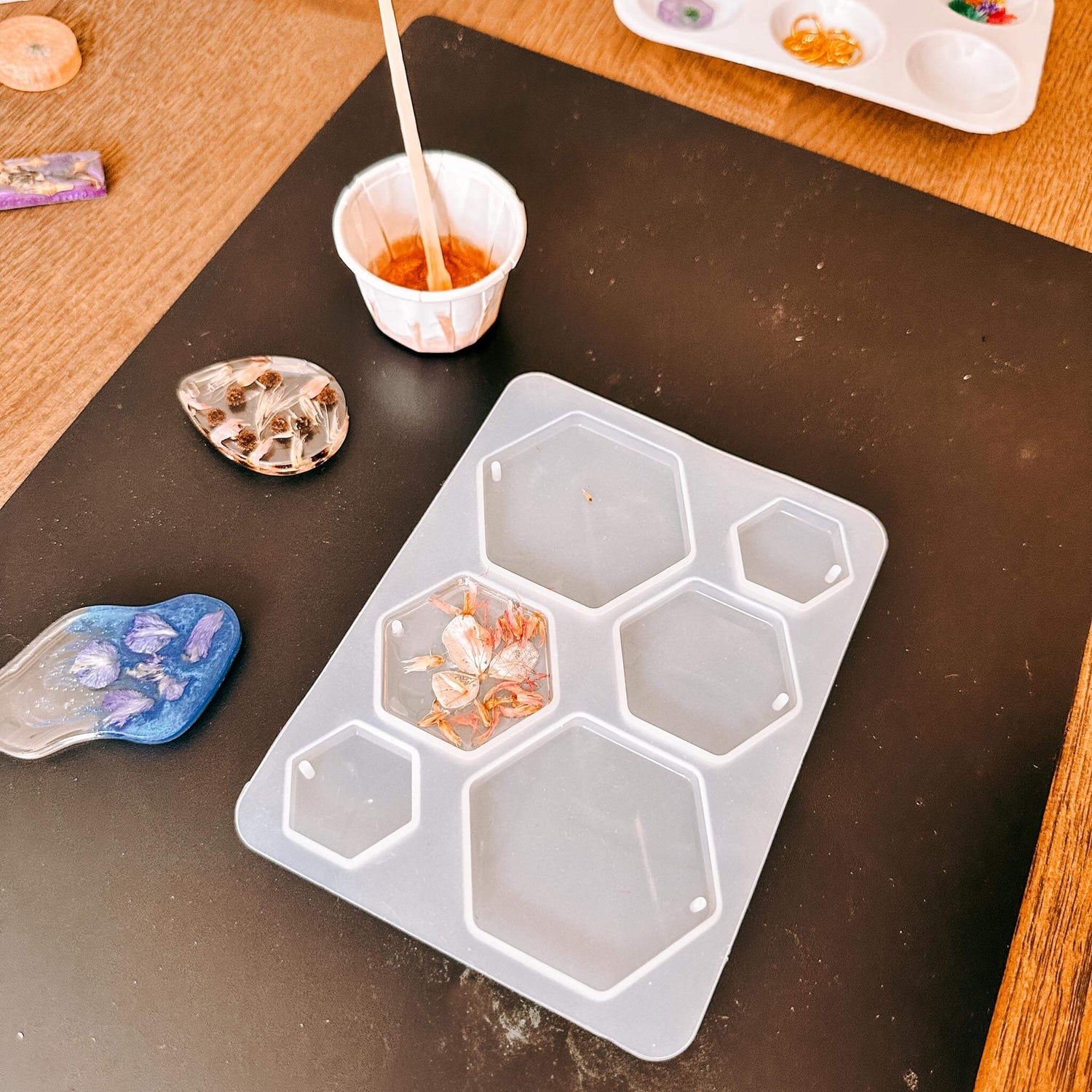 Gussform mit Resin-Anhängern und Werkzeugen daneben – resin jewelry, resin workshop, auch für Firmenevents.