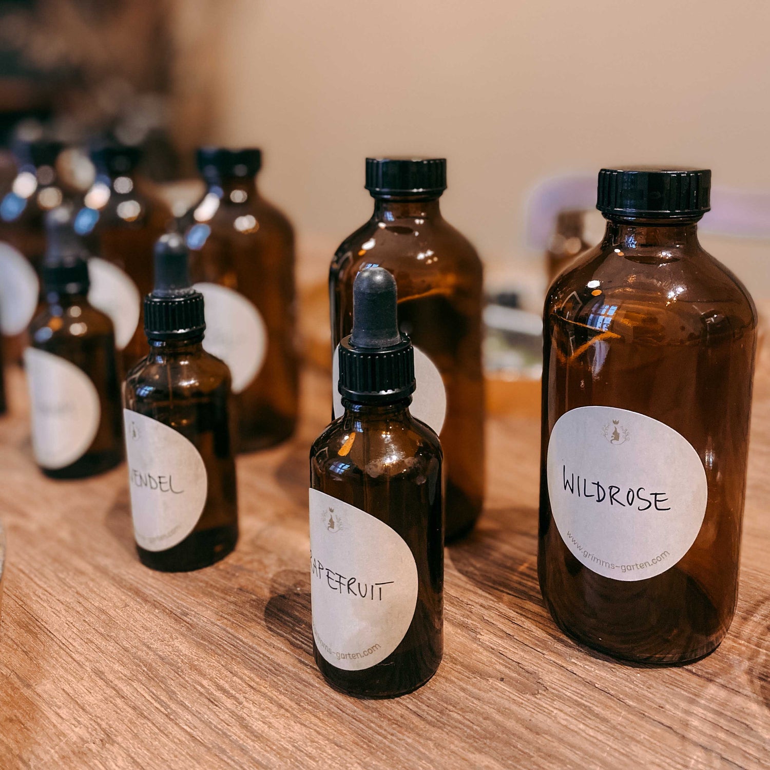 Kleine und große Flaschen mit Labels wie „Wildrose“ und „Grapefruit“ – naturkosmetik workshop, diy serum, ätherische öle.