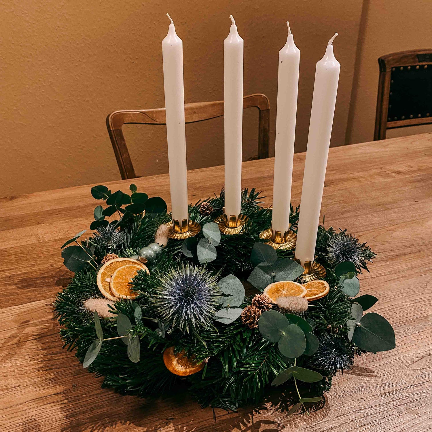 Adventskranz mit weißen Kerzen auf Tisch – DIY Box Sterntaler für natürliche Weihnachtsdeko.