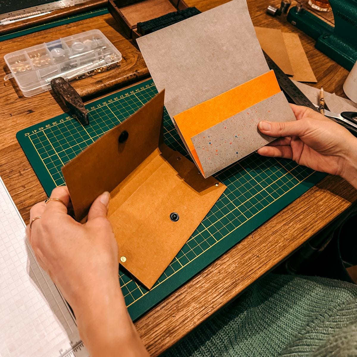 Fertiges Portemonnaie wird von Hand gehalten mit Schablone und Materialien – DIY Workshop, veganes Leder, Firmenevent.