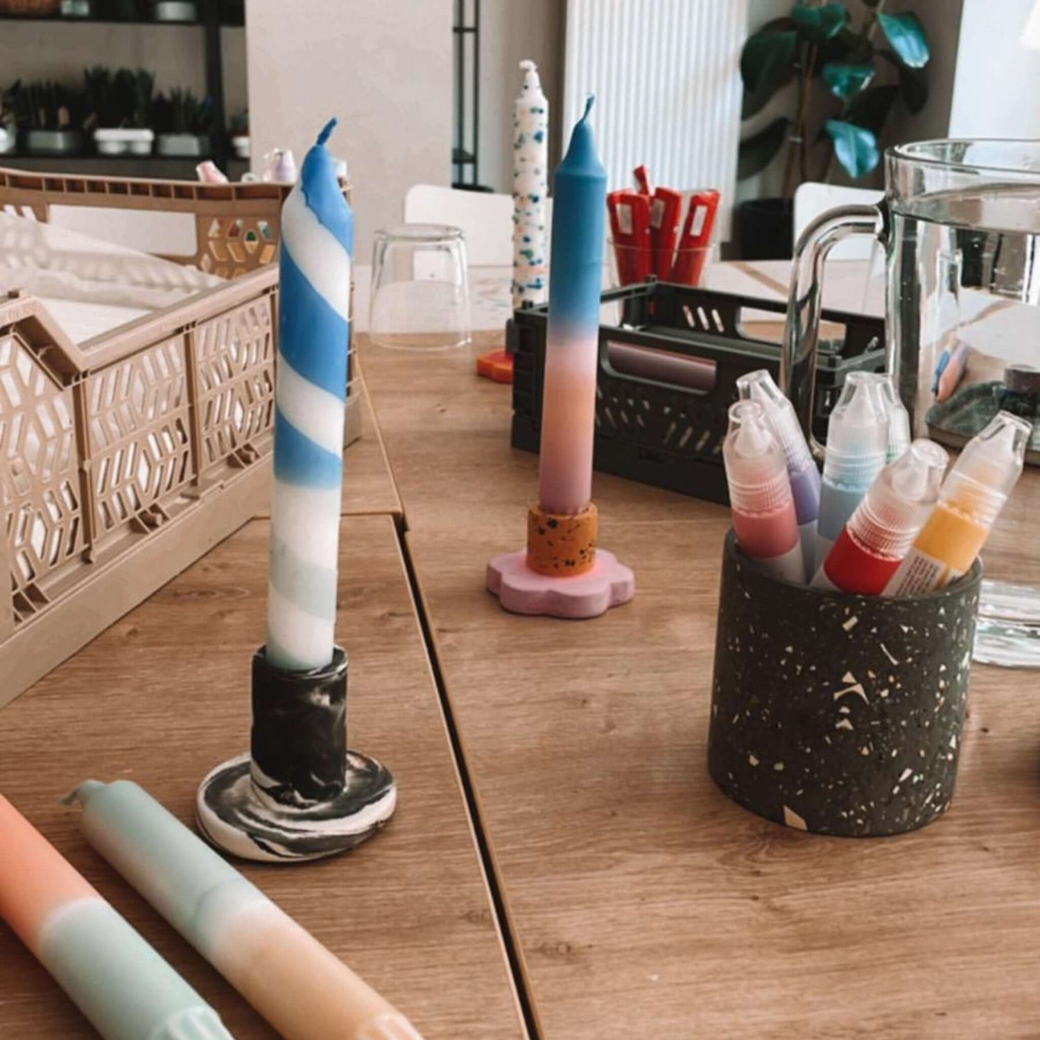 Kerzen im Ständer auf Holztisch mit Gefäß voller Stifte – dip dye kerzen, kerzen workshop berlin, kerzen färben.Auch als Firmenevent buchbar.