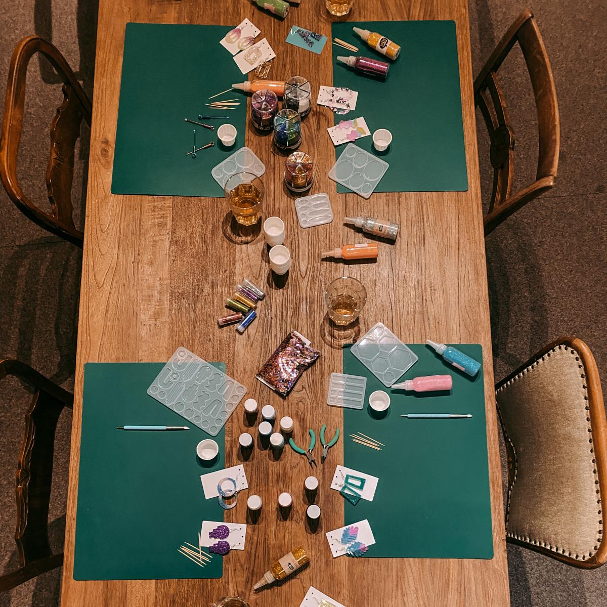 Tisch mit Arbeitsstationen und Materialien – Resin Schmuck Workshop für Ohrringe und Anhänger.