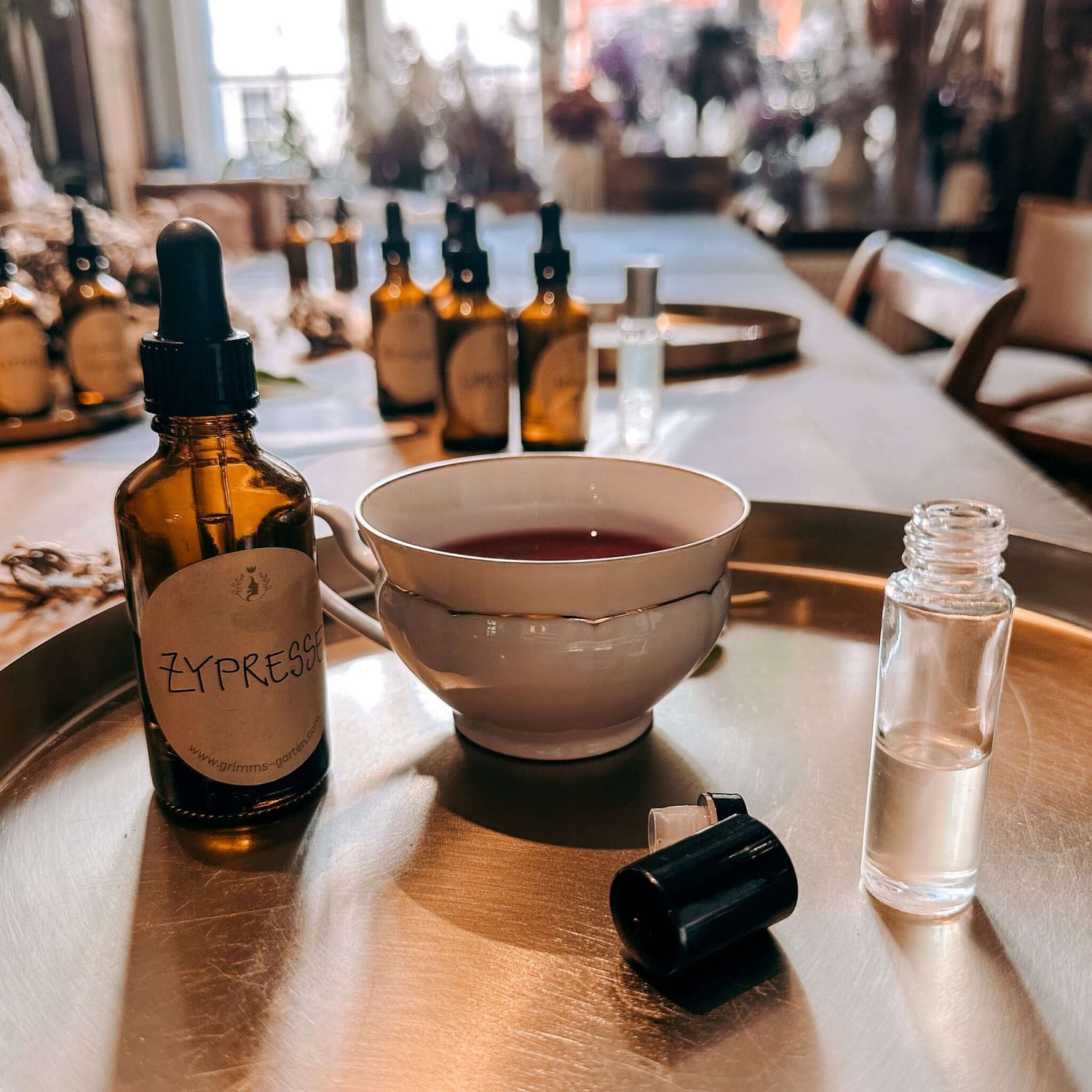 Tasse mit Ölmischung und Flaschen im Vordergrund, weitere Fläschchen im Hintergrund – rauhnächte workshop, ätherische öle, achtsamkeit.