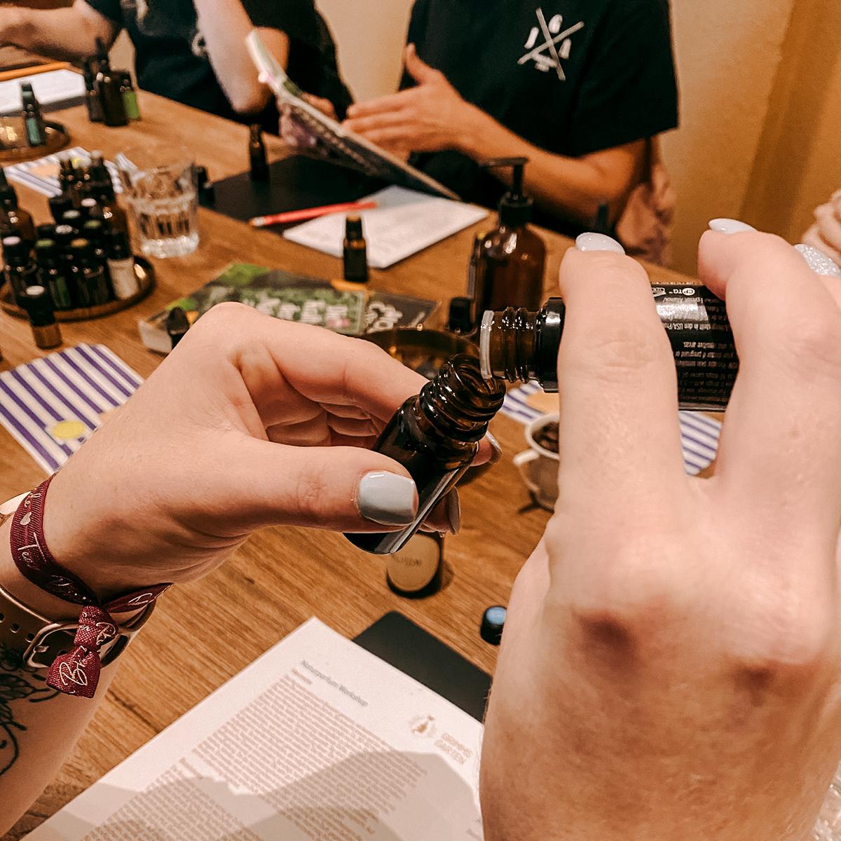 Zwei Hände befüllen kleine Flasche mit Flüssigkeit, Nahaufnahme – parfum selber machen, naturkosmetik workshop, diy duft, auch für Firmenevents.