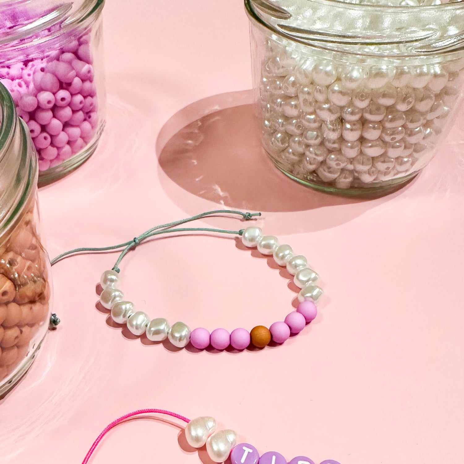 Drei Gläser mit bunten Perlen, Perlenarmband auf Tisch – Perlenschmuck Workshop Berlin, DIY Schmuck.