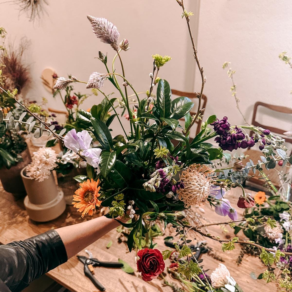 Großer Blumenstrauß mit mehreren Vasen und Sträußen im Hintergrund – DIY Workshop, Teamevent möglich.