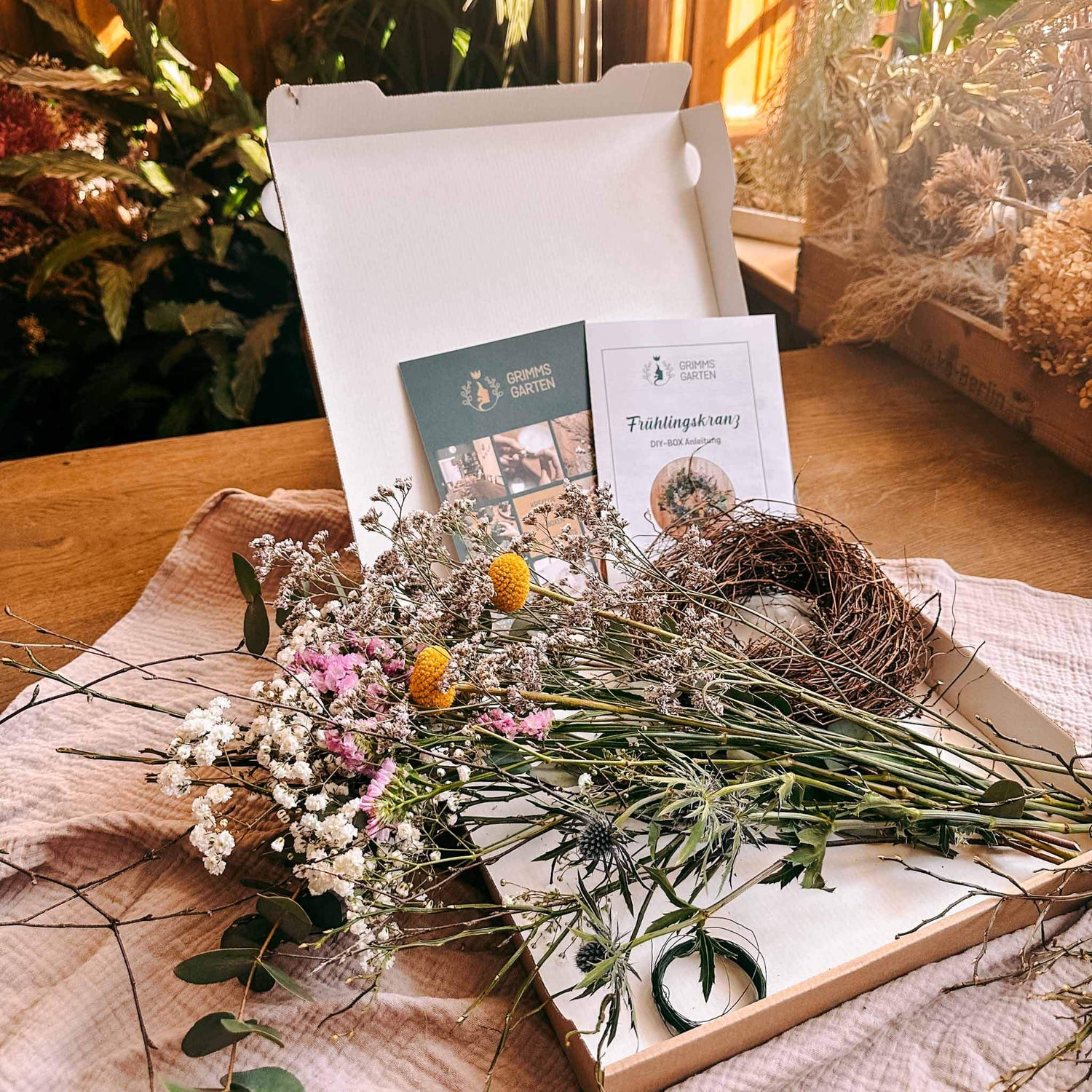 Offene DIY Frühlingskranz Box mit allen Materialien für kreative Frühlingsdeko auf Tisch.