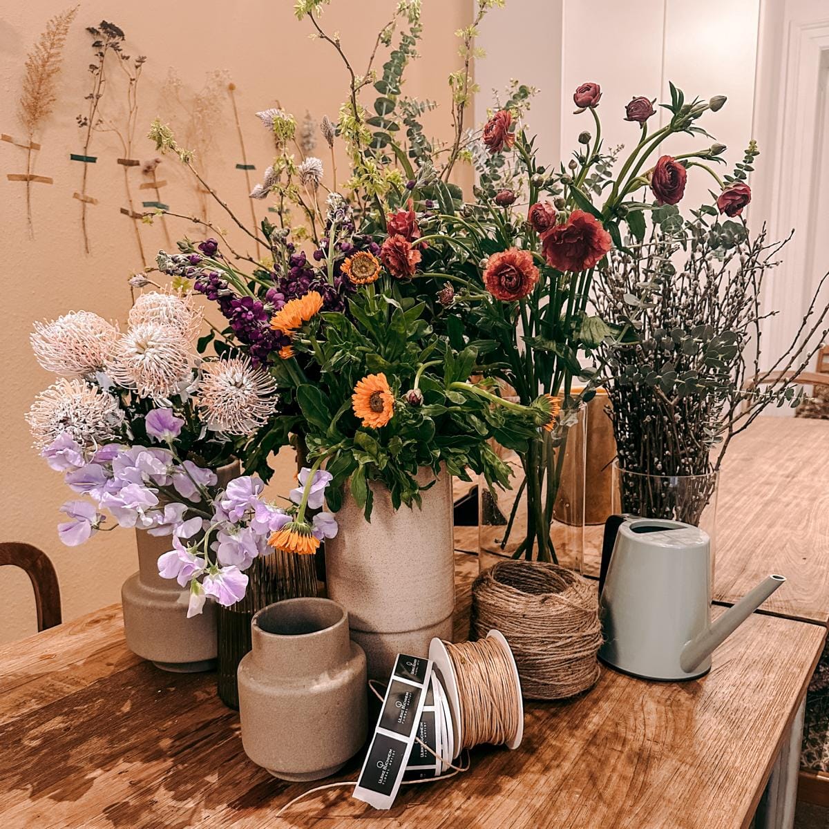 Mehrere fertige Blumensträuße und Vasen auf Tisch – Flower Bouquet Workshop, Teamevent möglich.