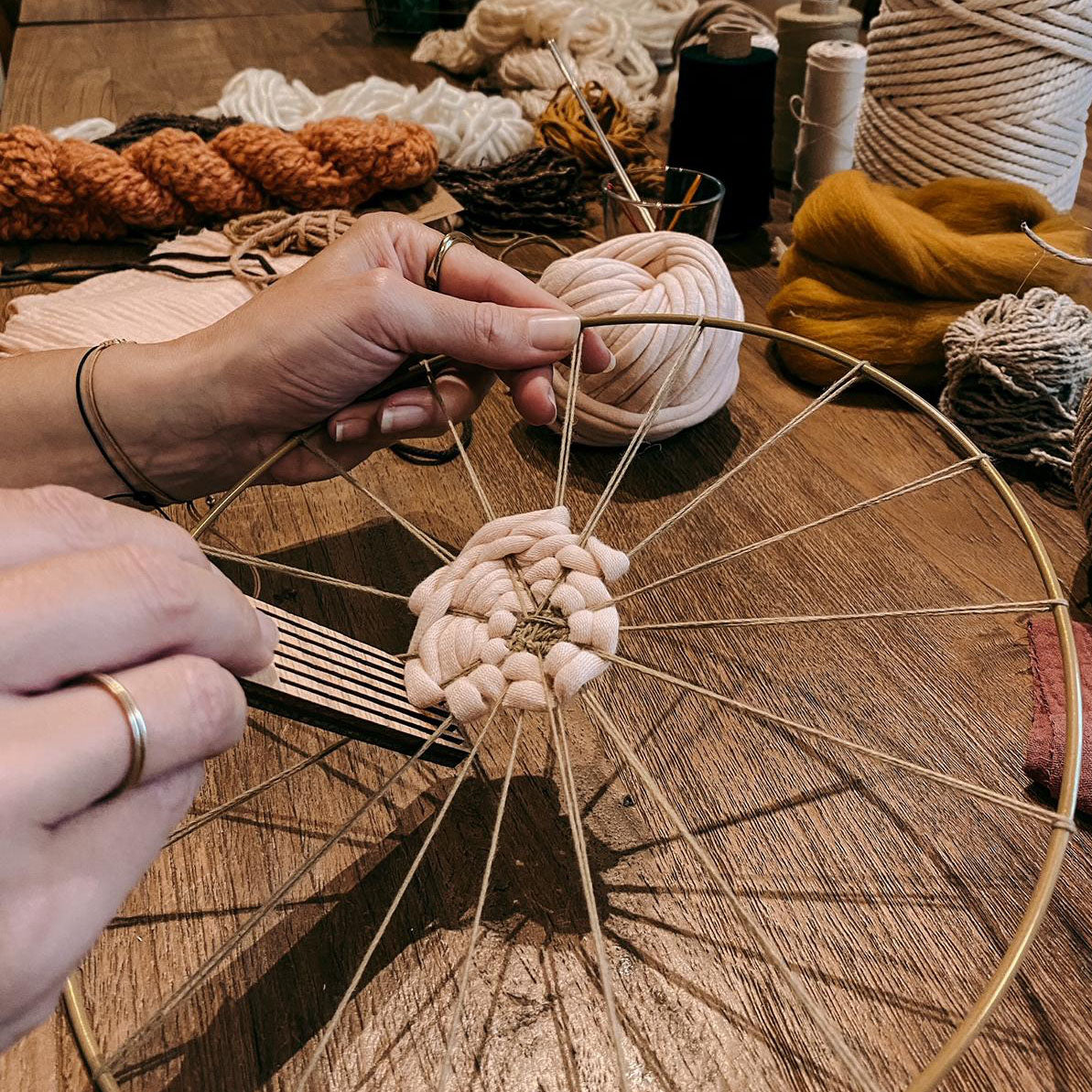 Angefangener Rundweben von zwei Händen bearbeitet – DIY Boho Wandkunst Kurs Berlin.