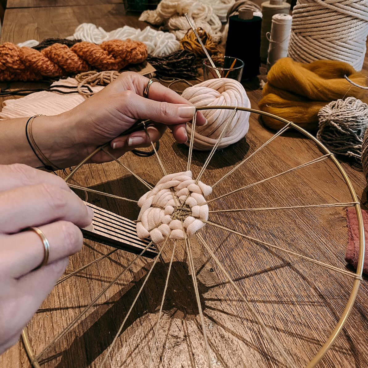 Angefangener Rundweben von zwei Händen bearbeitet – DIY Boho Wandkunst Kurs Berlin.