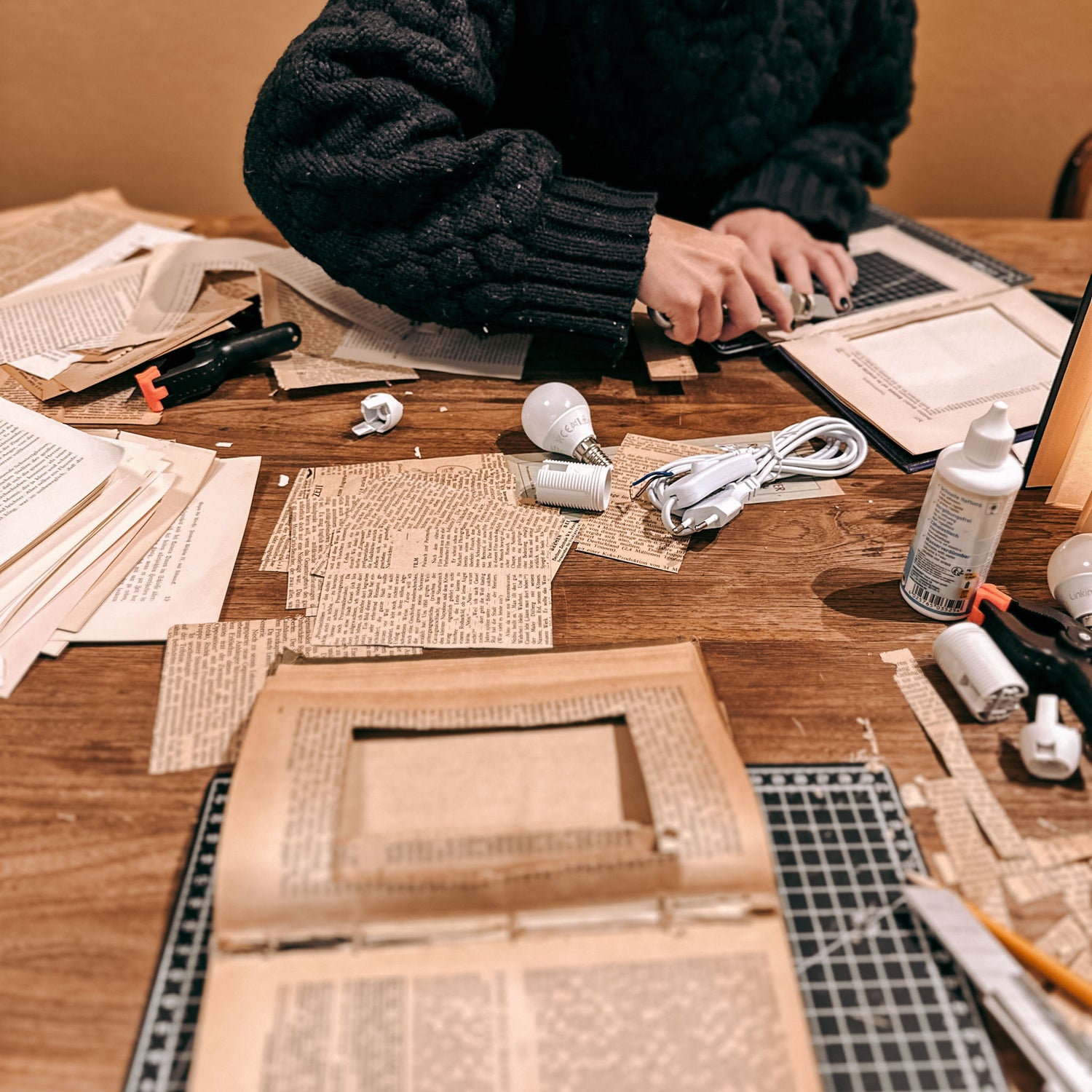 Personen fertigen Buchlampen am Tisch mit Materialien – buchlampe workshop, upcycling design, diy lampe. Auch für Firmenevents.