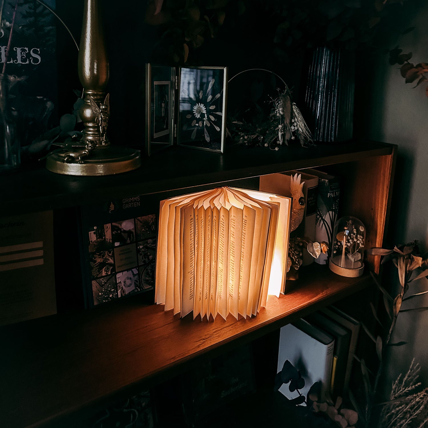 Fertige Buchlampe auf Tisch mit Deko, dunkler Hintergrund – buchlampe, upcycling deko, nachhaltiges design. Auch für Firmenevents.