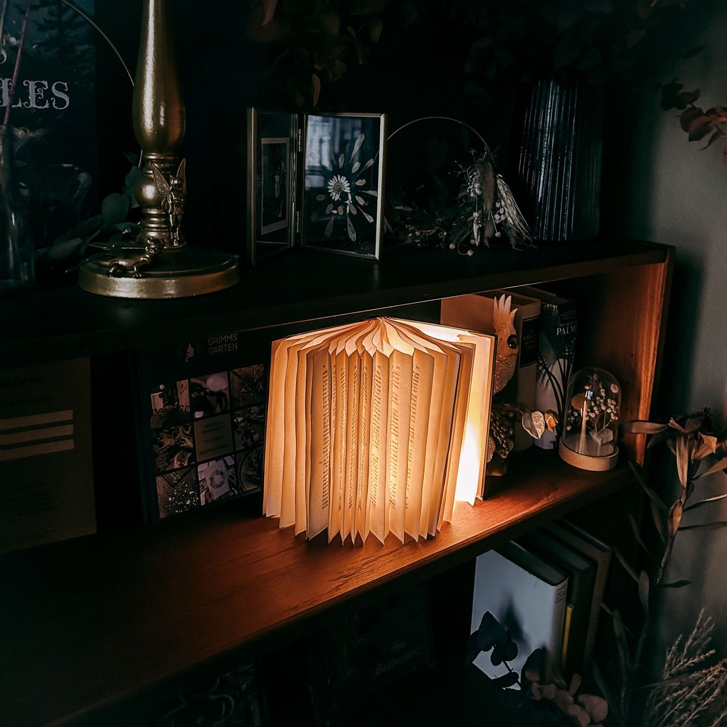 Fertige Buchlampe auf Tisch mit Deko, dunkler Hintergrund – buchlampe, upcycling deko, nachhaltiges design. Auch für Firmenevents.