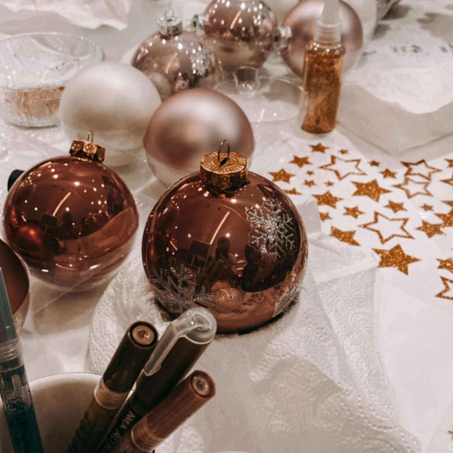 Mehrere Kugeln auf Tisch mit Stiften, Glitzer und Stickern – DIY Christbaumschmuck Workshop.