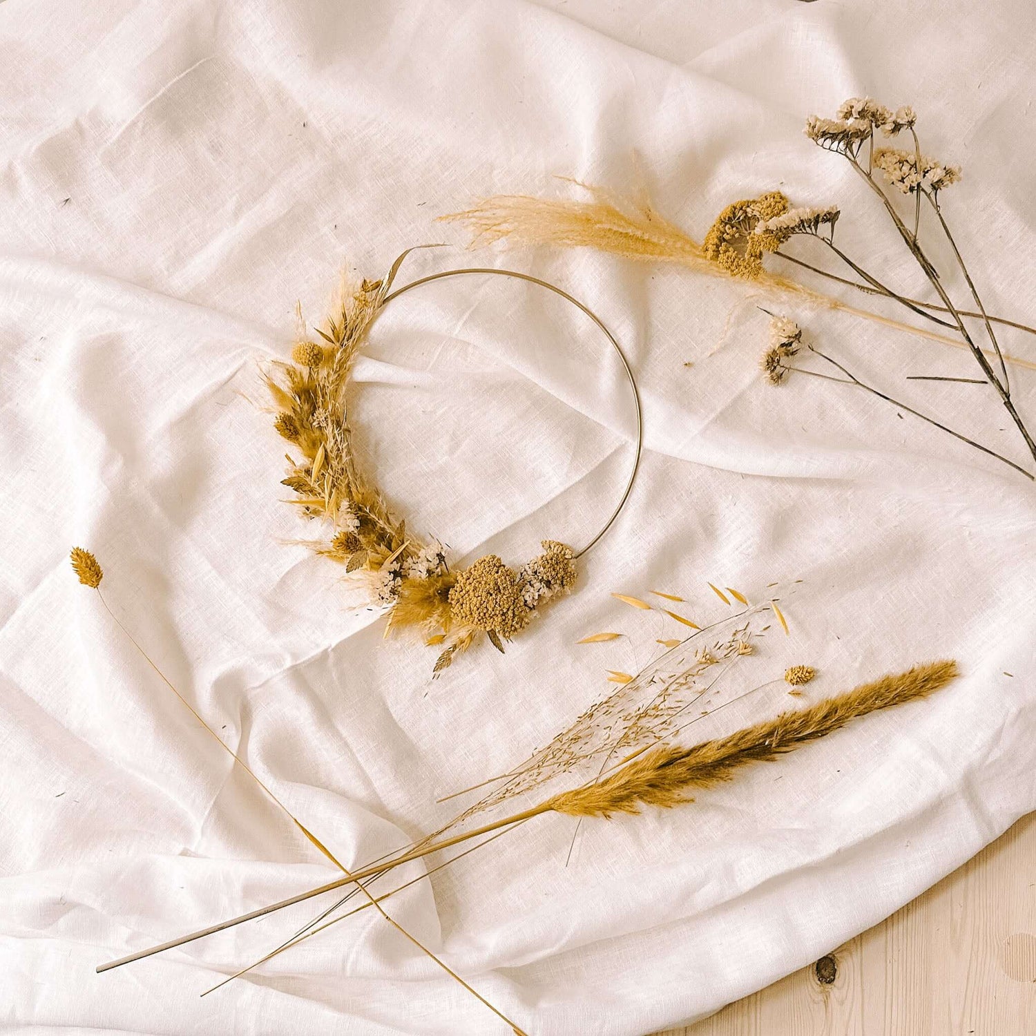 Gelber Trockenblumenkranz auf Tuch, weitere gelbe Blumen drumherum, kreativer DIY Workshop bei Grimms Garten Berlin