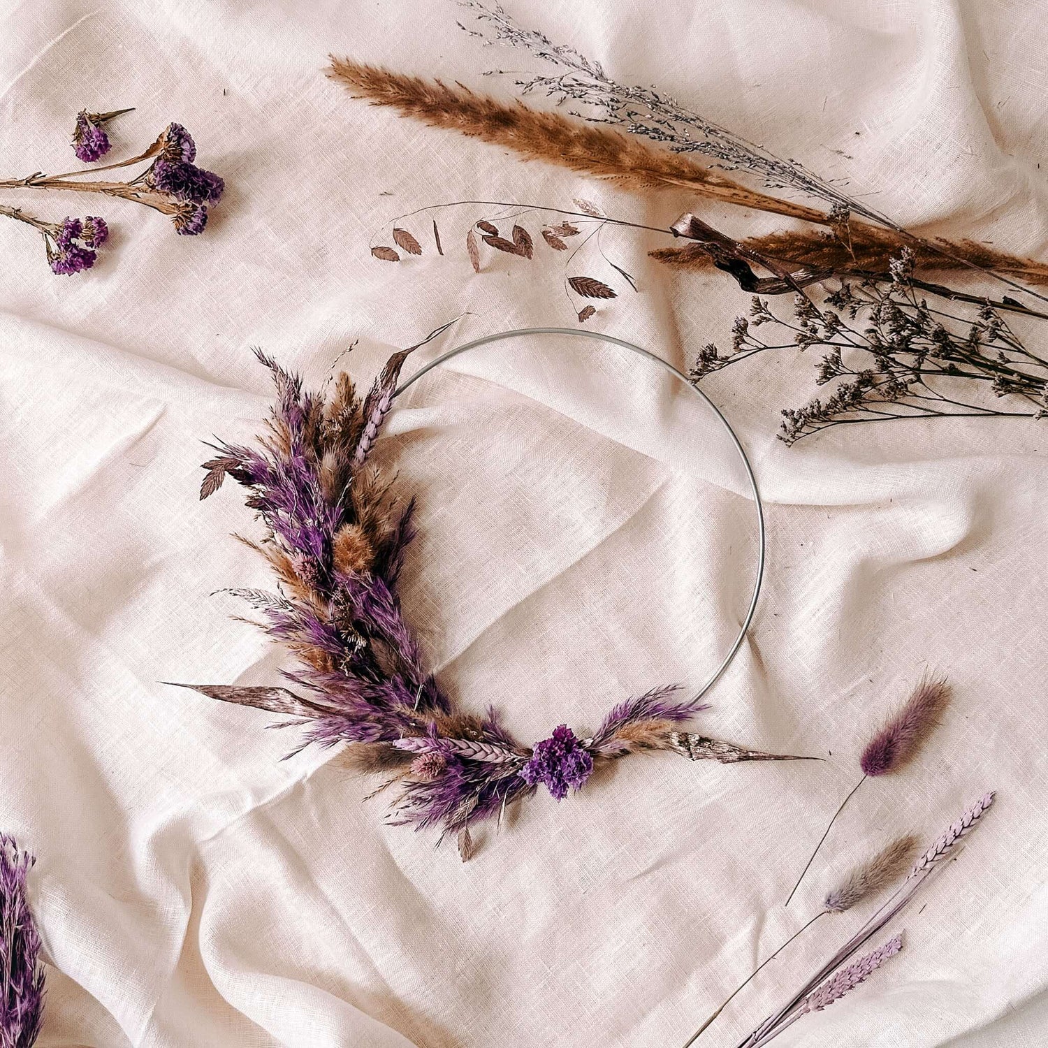 Fertiger Trockenblumenring Violetta mit lila Blüten auf weißem Tuch – kreative Wanddekoration DIY.