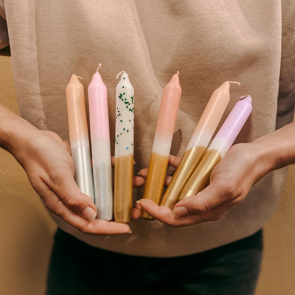 Verschiedene Dip-Dye-Kerzen in Händen gehalten, DIY Kerzenworkshop bei Grimms Garten Berlin