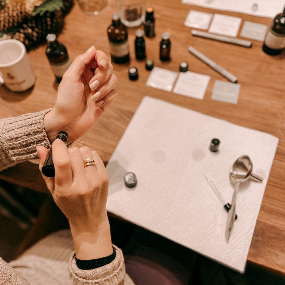 Hand trägt Roll-on auf, Materialien liegen im Hintergrund – naturparfum, ätherische öle, diy duft workshop, auch für Firmenevents.