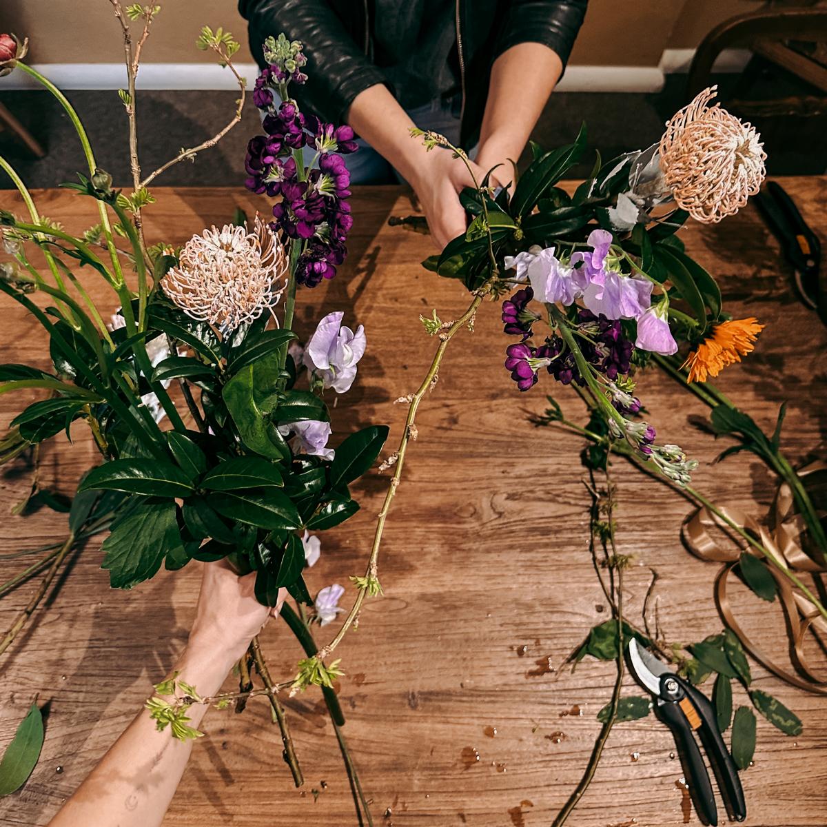 Zwei Personen präsentieren ihre selbstgestalteten Blumensträuße – Workshop für Teams oder Einzelpersonen.