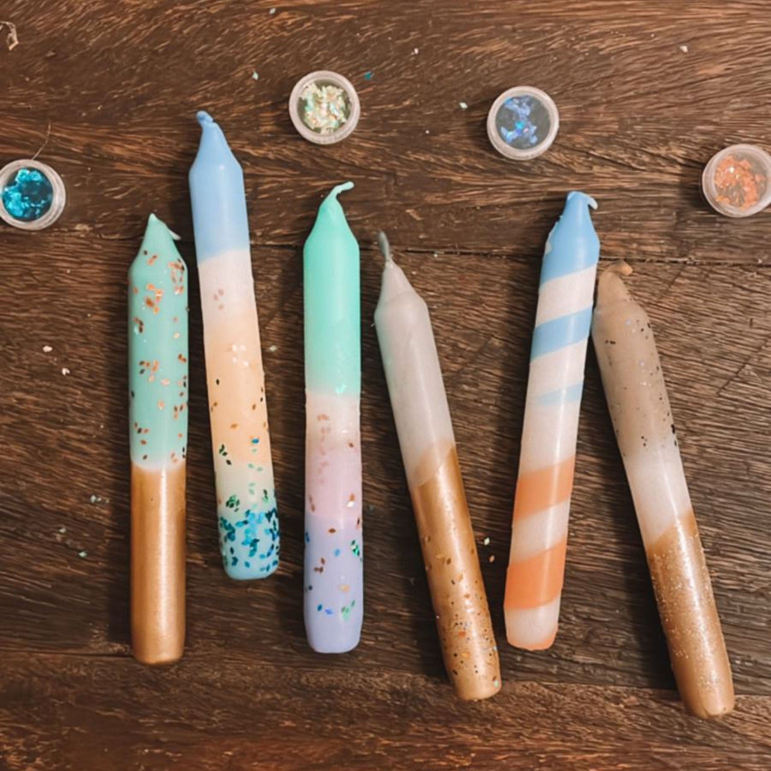 Mehrere fertig gefärbte Adventskerzen auf Tisch – dip dye adventskerzen, kerzen färben, adventskerzen selber machen.Auch als Firmenevent buchbar.