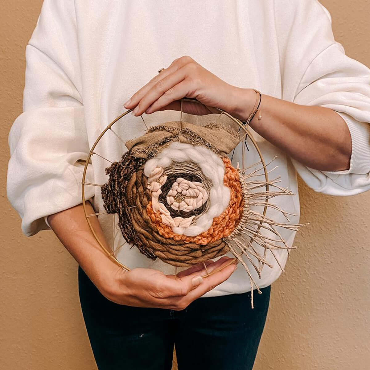 Person hält fertiges Rundweben hoch – kreative Handarbeit beim Rundweben Workshop für Zuhause.