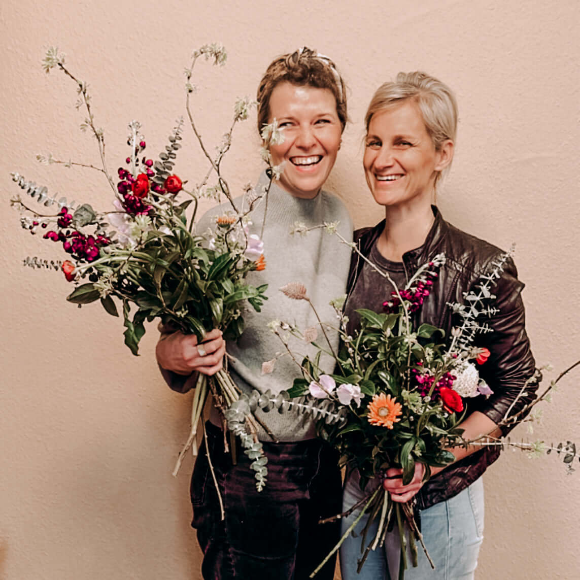 Zwei Frauen halten jeweils ihren selbstgemachten Blumenstrauß – kreativer Workshop, auch als Teamevent.