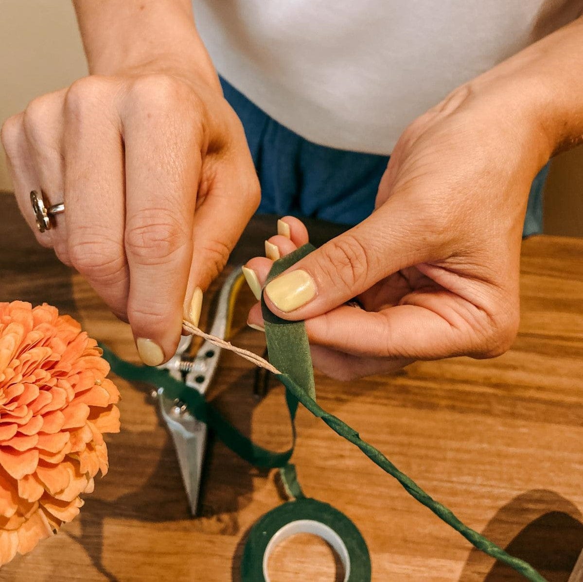 Hand wickelt grünes Band um Faden, kreativer DIY Workshop bei Grimms Garten Berlin
