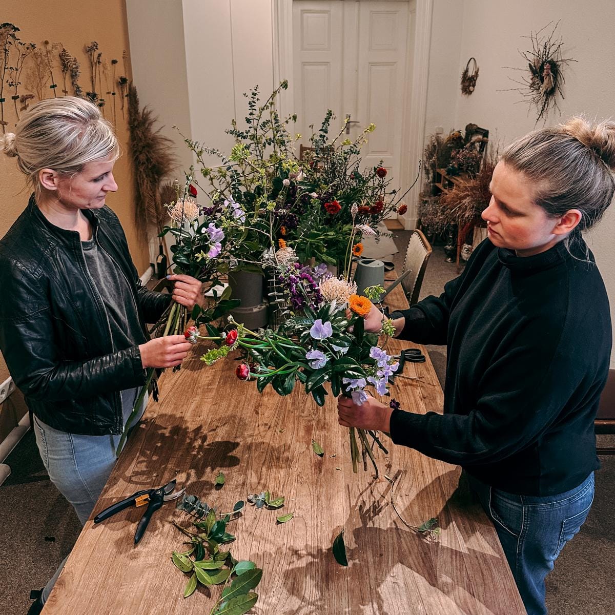 Zwei Personen kreieren ihre Blumensträuße in verschiedenen Farben – kreativer Workshop für Teams.
