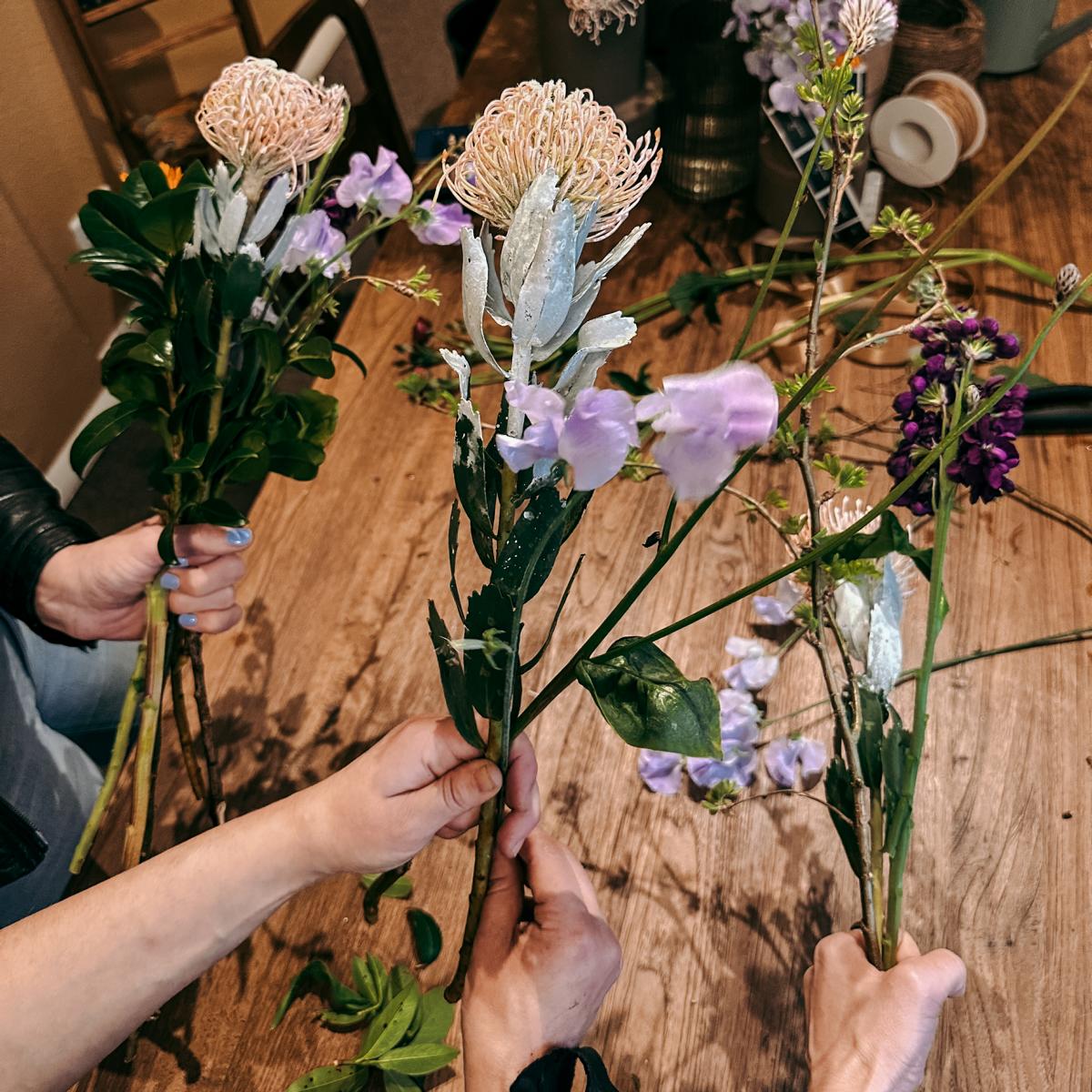 Drei Personen präsentieren ihre angefangenen Sträuße – Workshop für Blumenliebhaber, auch als Teamevent.