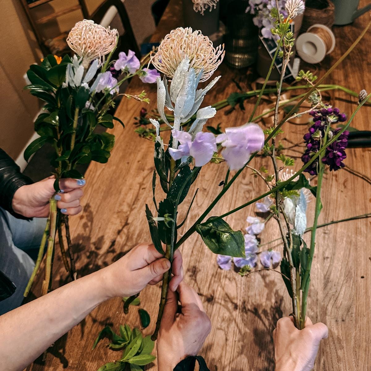 Drei Personen präsentieren ihre angefangenen Sträuße – Workshop für Blumenliebhaber, auch als Teamevent.