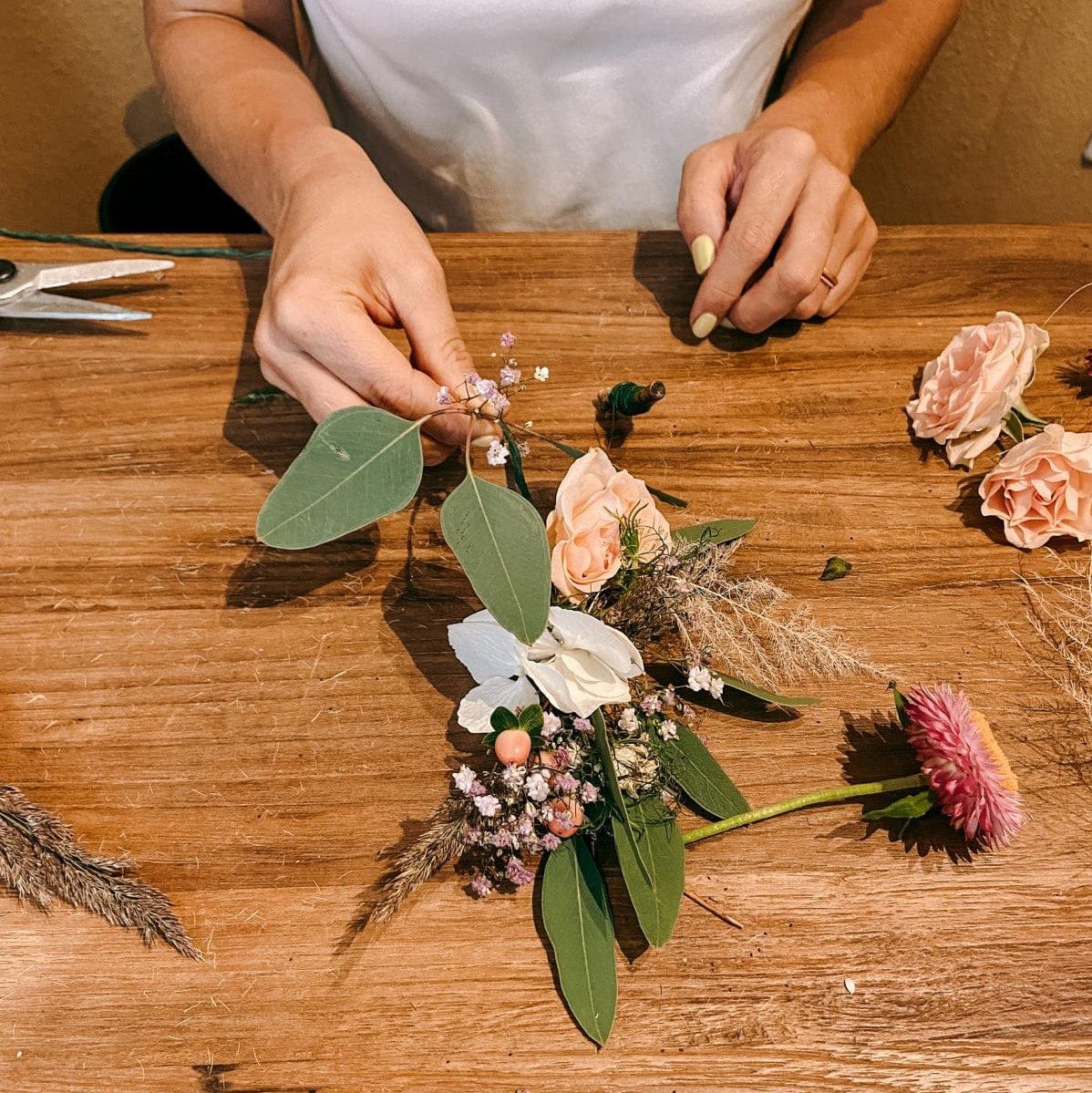 Hände binden Eukalyptus an kleinen Blumenstrauß, DIY Blumenworkshop bei Grimms Garten Berlin