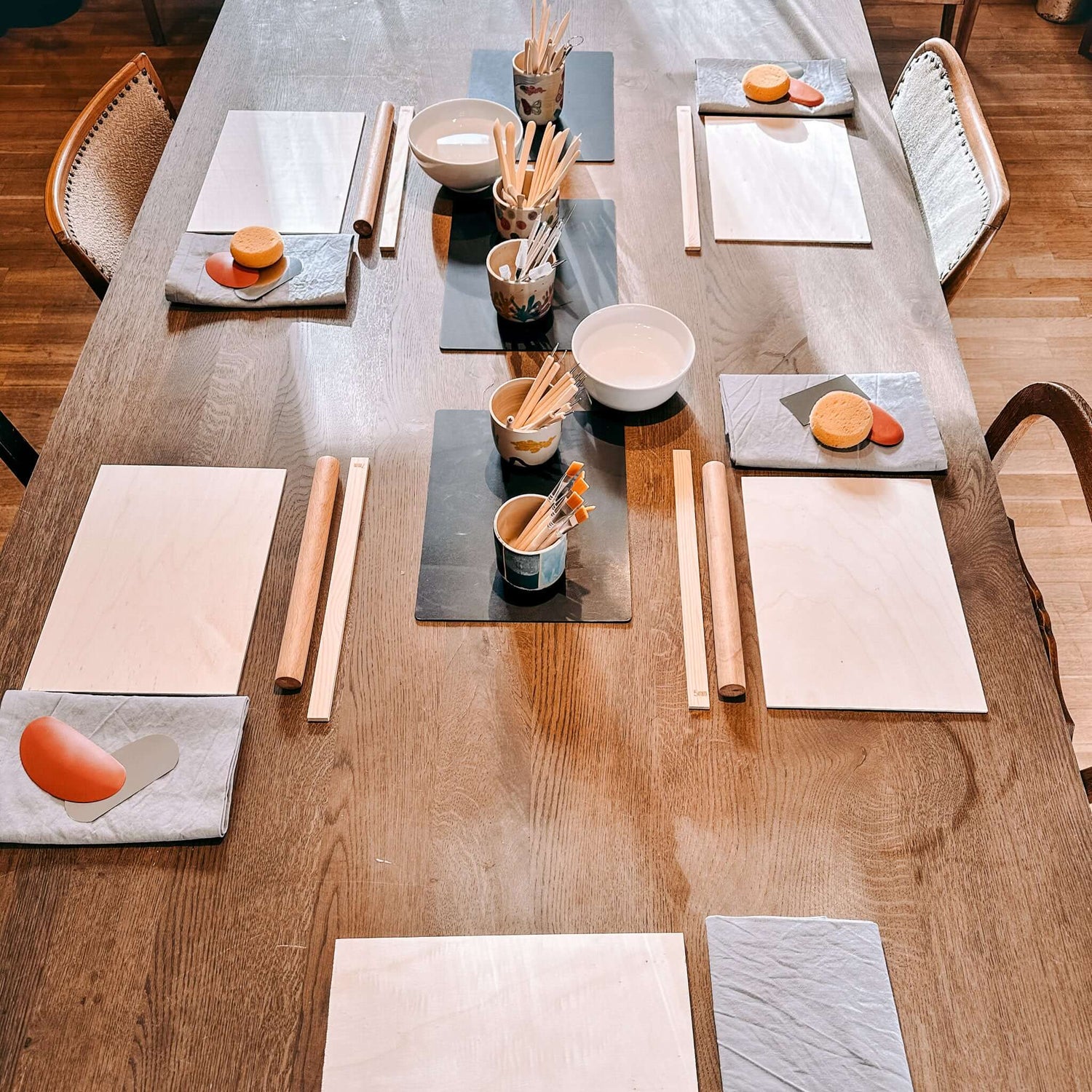 Fünf vorbereitete Arbeitsplätze mit Ton, Werkzeugen und Materialien – Start Töpferkurs Englisch Grimms Garten