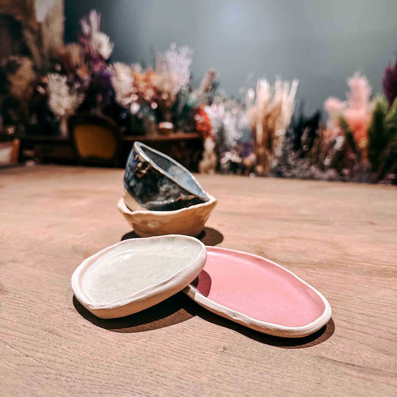 Vier handgefertigte Töpferprojekte in unterschiedlichen Formen und Farben auf einem Tisch angeordnet.