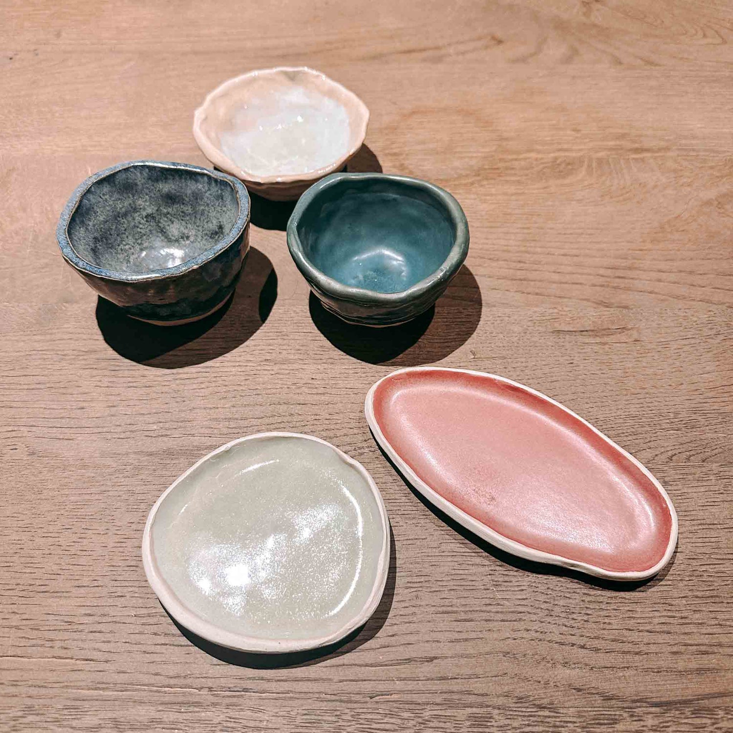 Drei handgefertigte Kaffeetassen und zwei Untersetzer auf Tisch – Töpferkurs in Berlin.