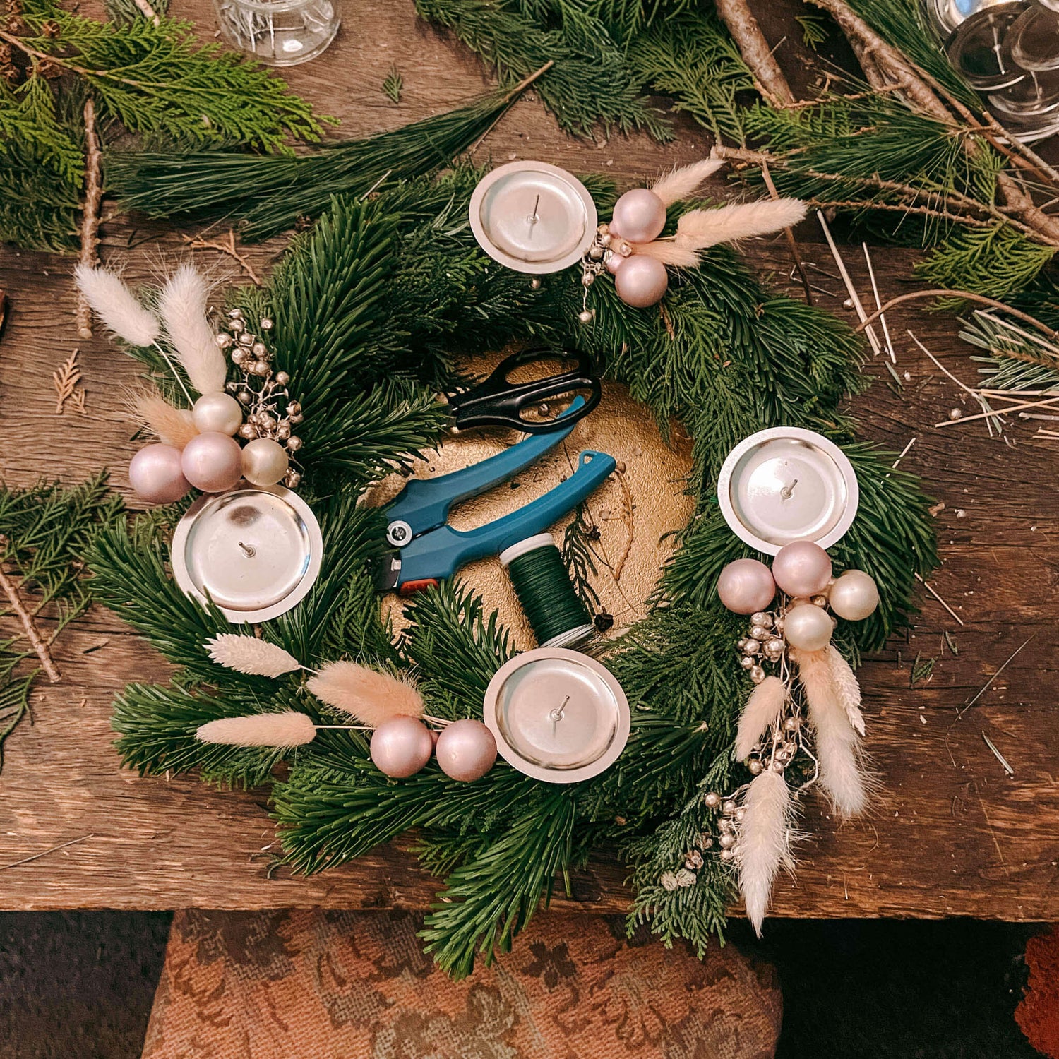 Detailfoto von Kerzen, Zapfen und Trockenblumen auf adventskranz modern.Auch als Firmenevent buchbar.