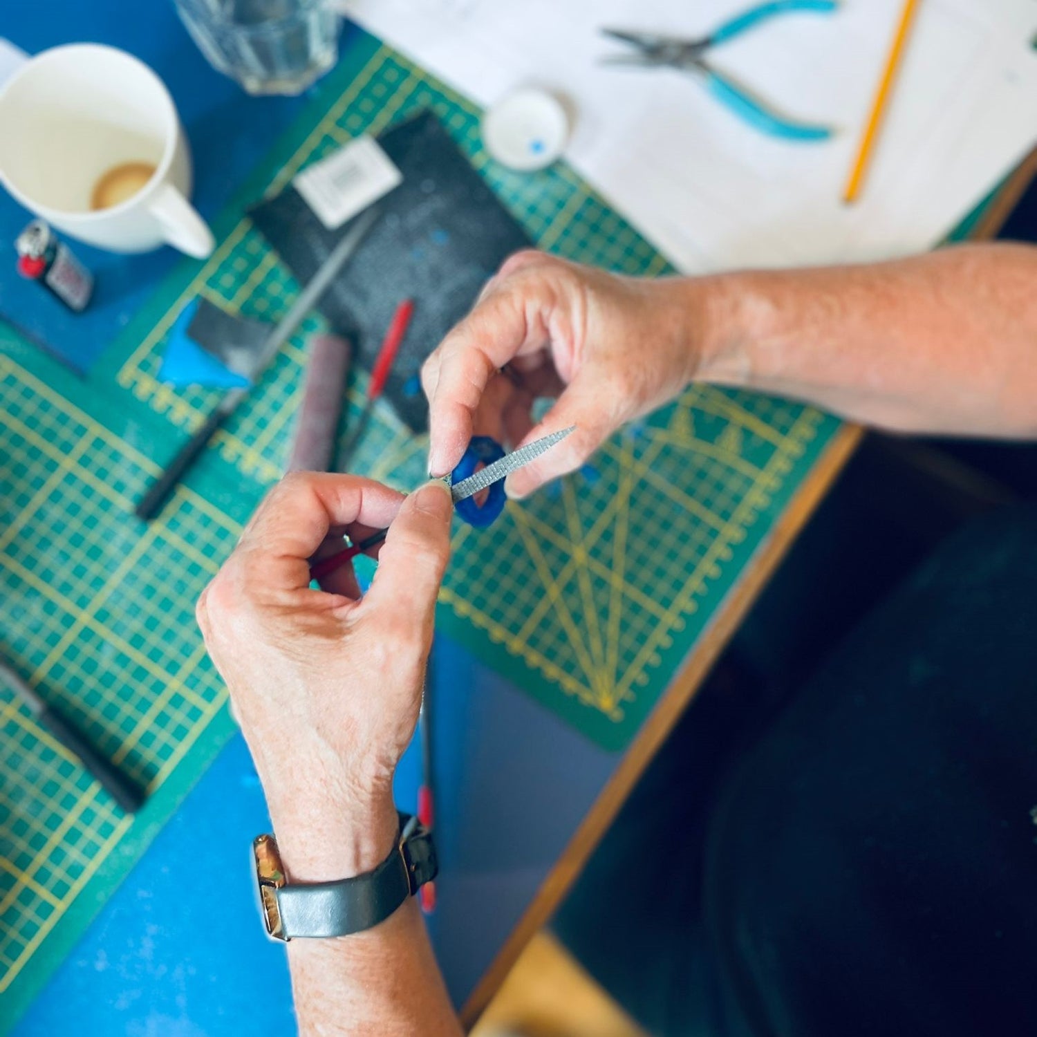 Zwei Hände formen Ring aus Wachs mit Werkzeugen im Hintergrund – DIY Schmuck, Ring selbst gestalten, Goldschmiedekurs.