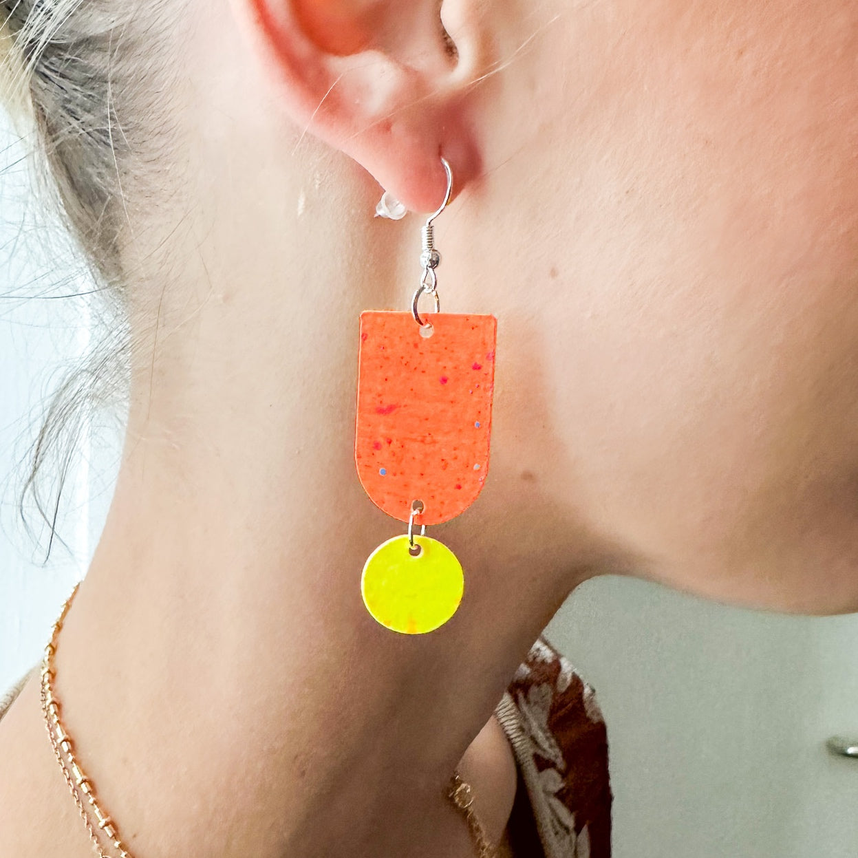 Nahaufnahme Ohr mit zweifarbigen Ohrringen in Orange und Gelb – DIY Ohrring Workshop.