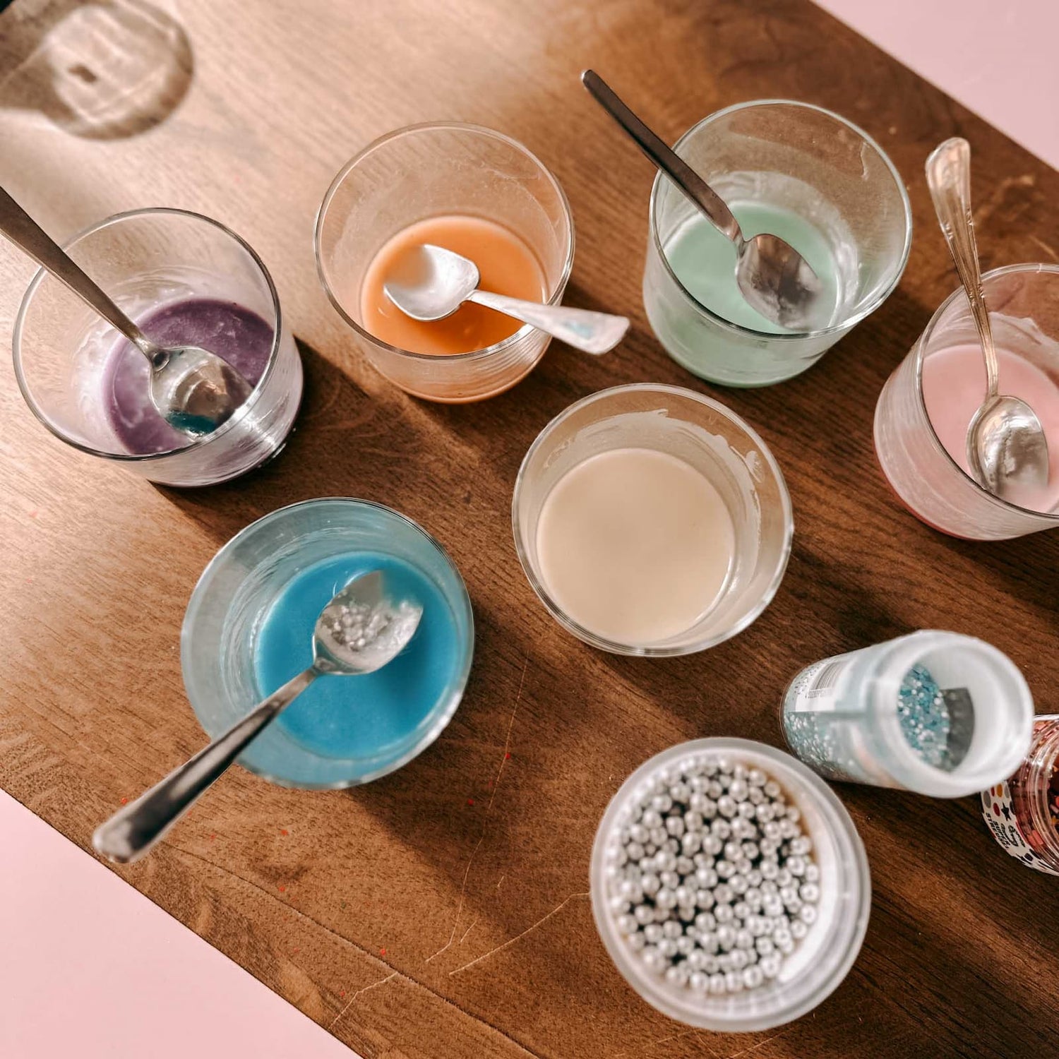 Mehrere Gläser mit verschiedenfarbigem Zuckerguss und silbernen Zuckerperlen in Bechern beim Osterkekse Workshop von GRIMMS GARTEN, kreativer Backkurs in Berlin