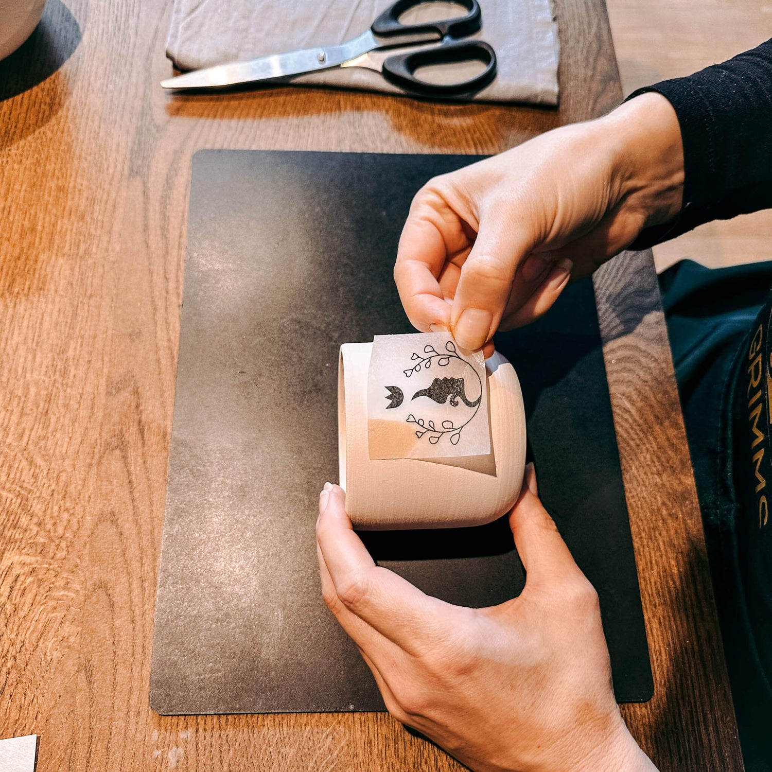 Hände übertragen Motiv vom Papier auf Keramikbecher – DIY Keramik Workshop Berlin, kreativ Keramik bemalen