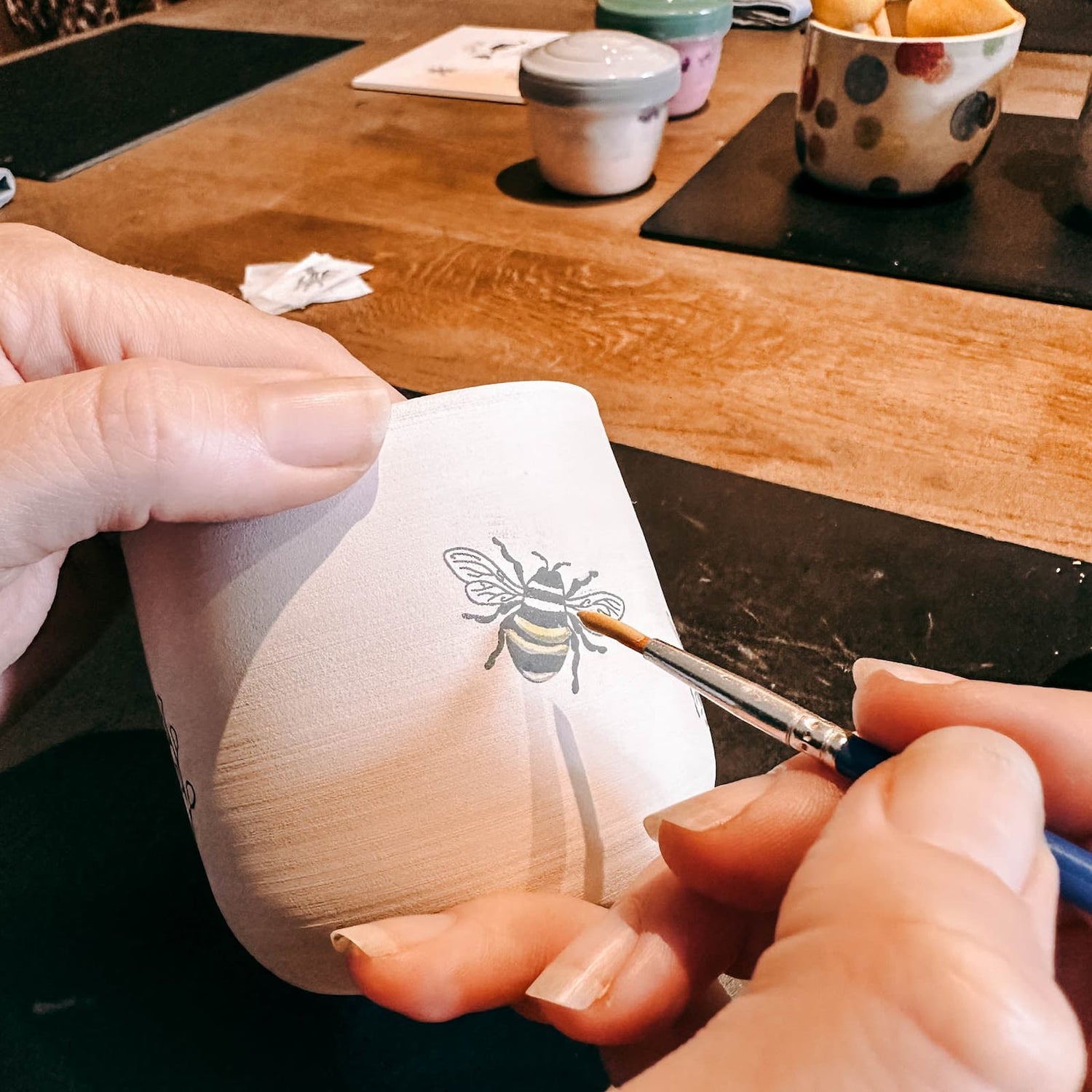 Hand malt Biene auf Keramikbecher – DIY Keramik Workshop Berlin, kreativ Keramik bemalen