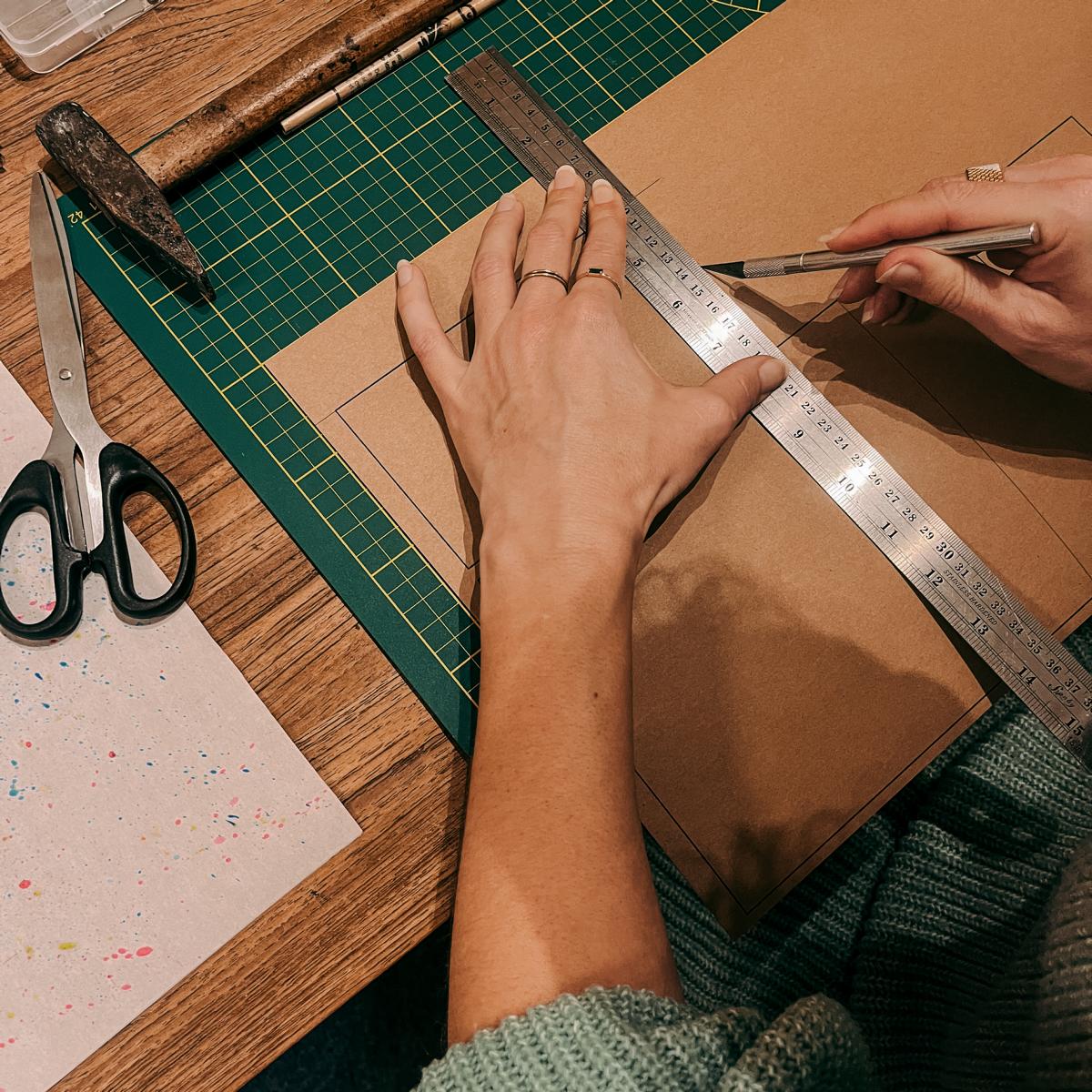 Zwei Hände zeichnen Form auf veganes Leder mit Lineal und Stift – DIY Portemonnaie Workshop, nachhaltiges Leder.