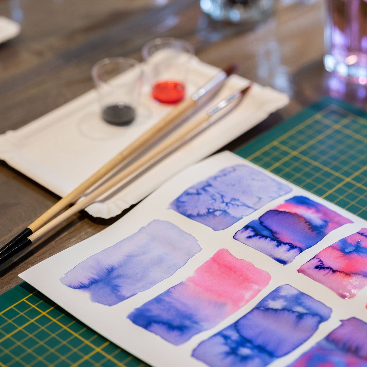 Nahaufnahme Aquarellbild mit bunten Blumen, Pinsel und Farben im Hintergrund – Flower Bouquet Workshop.