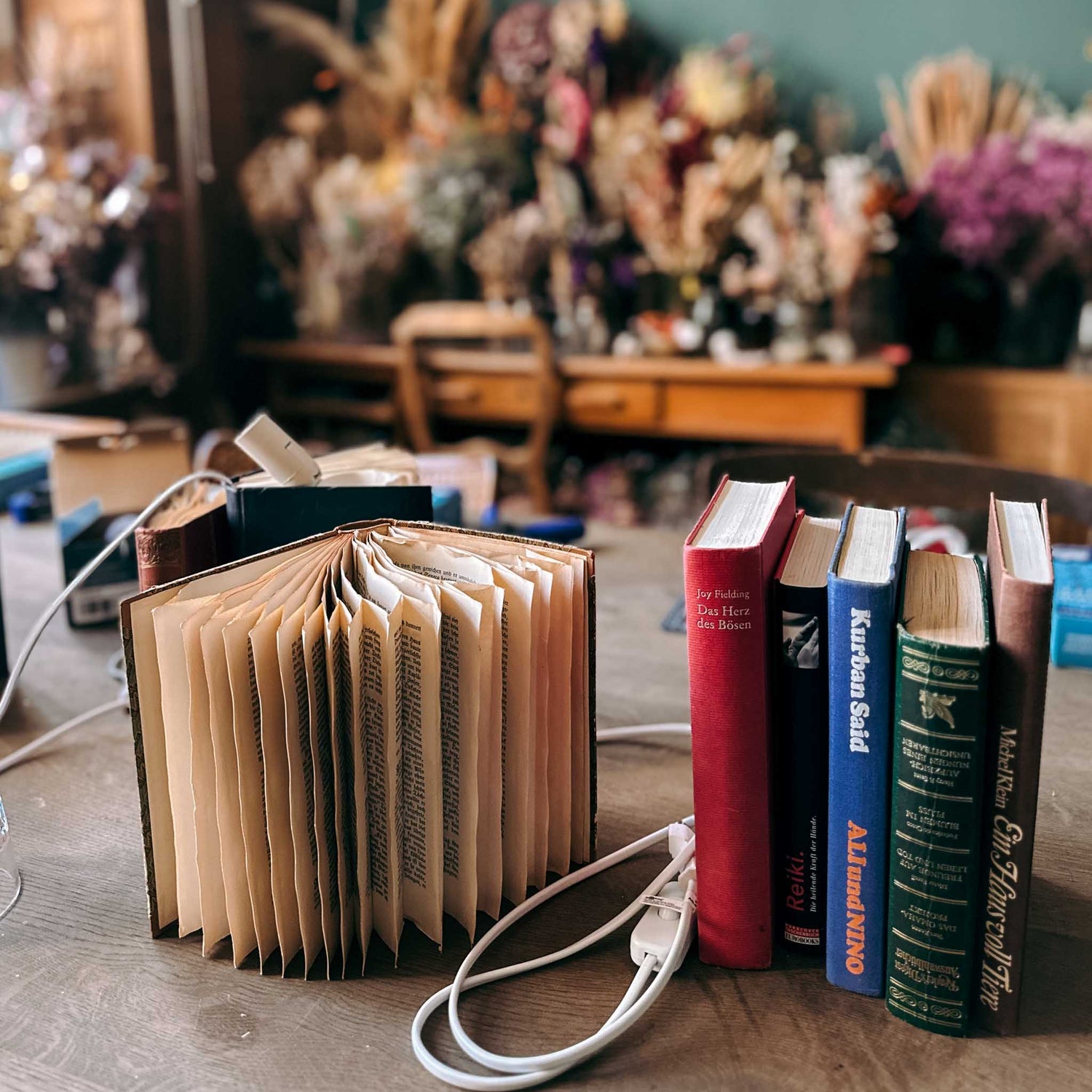 Buchlampe auf Tisch mit fünf Büchern in bunten Farben – buchlampe, diy lampe, nachhaltiges upcycling. Auch für Firmenevents.