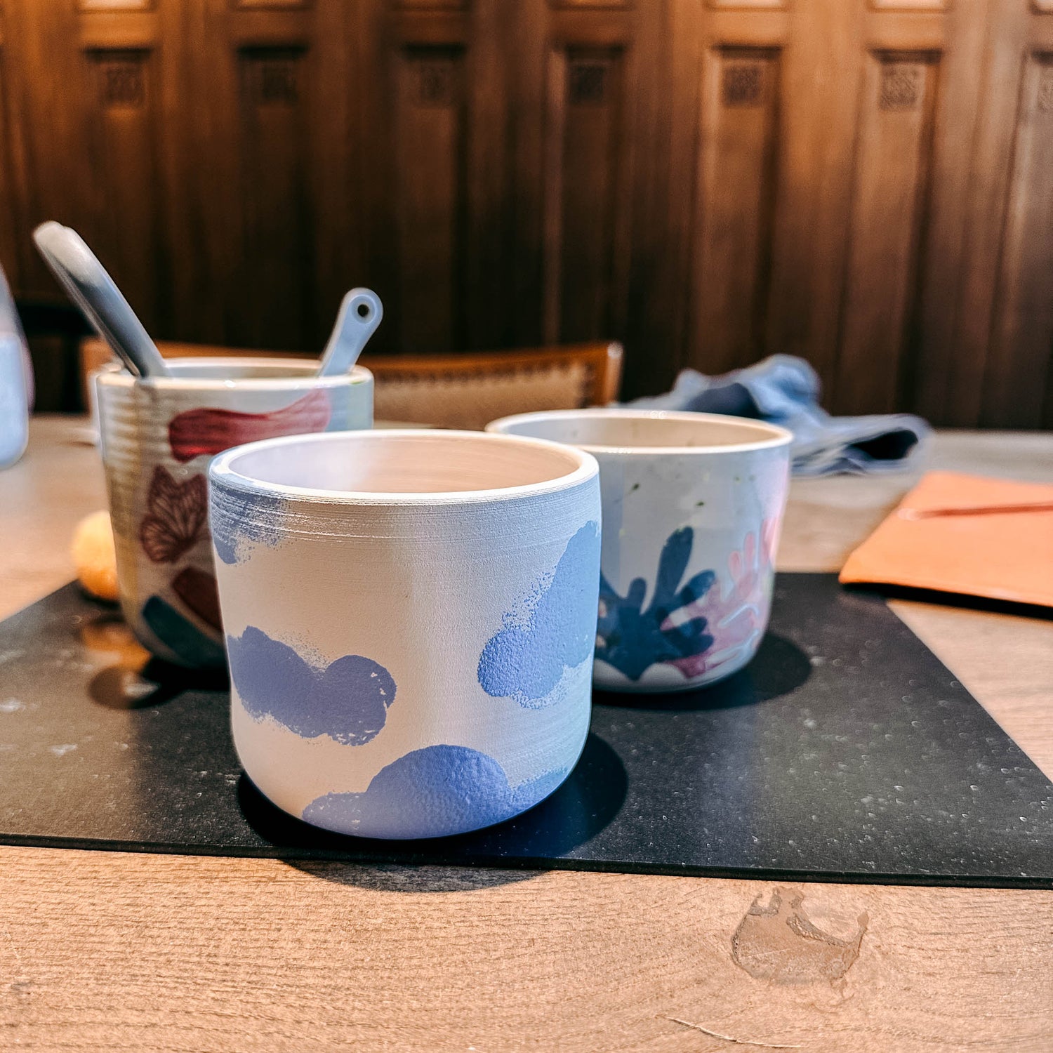 Keramikbecher mit blauen Wolken, dahinter weiterer Becher mit anderem Motiv – DIY Keramik Workshop Berlin