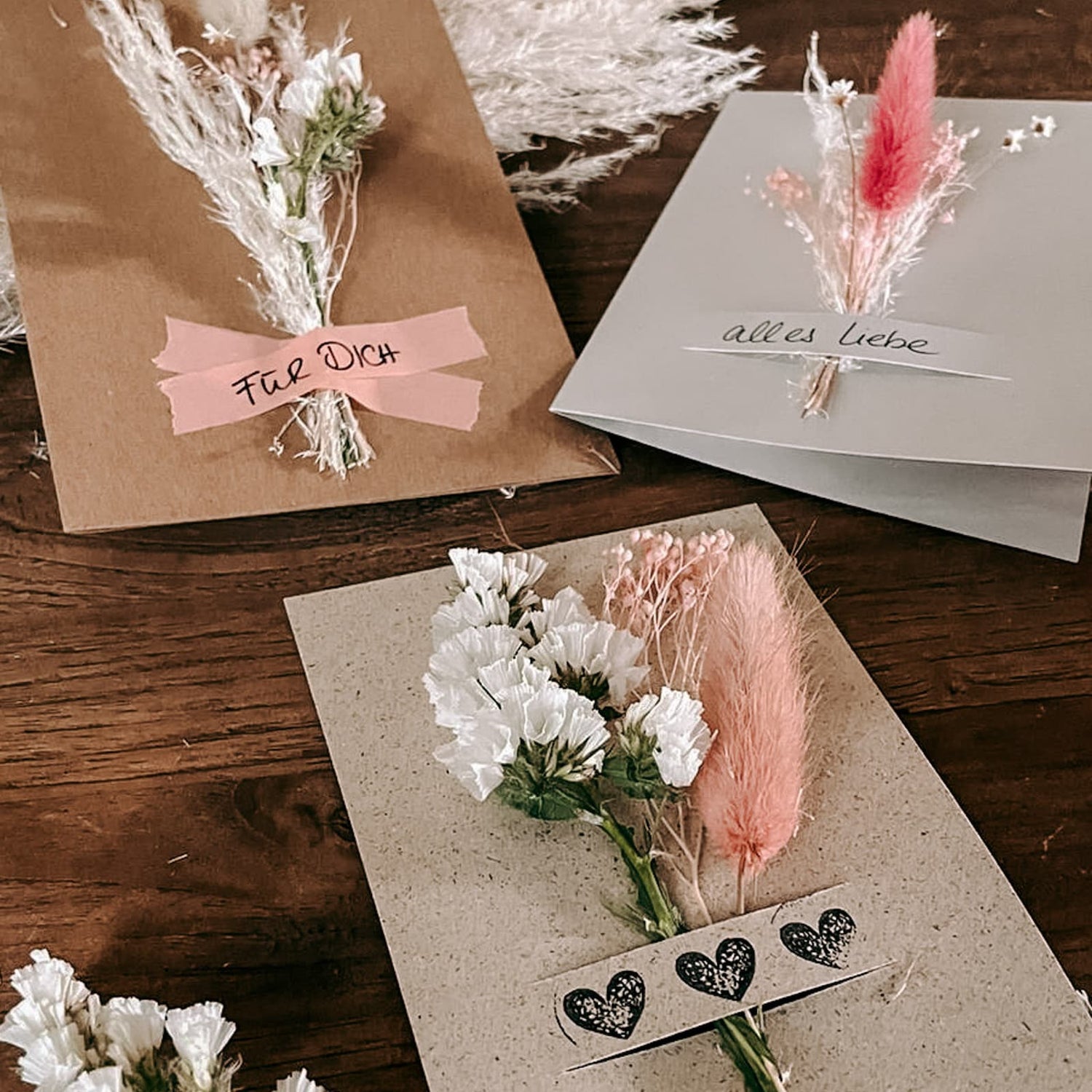 Drei Postkarten mit kleinen Trockenblumensträußen und Schriftzügen wie „Für dich“ und „Alles Liebe“ beim kreativen Postkarten Workshop von GRIMMS GARTEN in Berlin