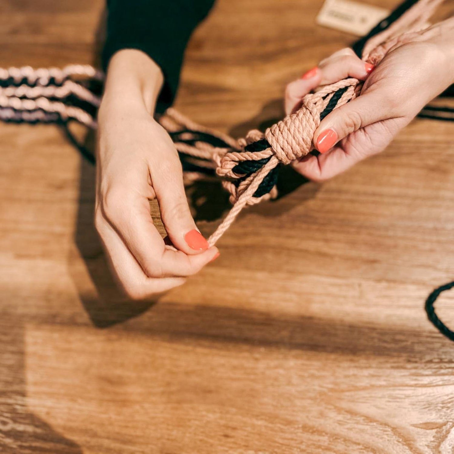 Hände knüpfen Makrameeampel – DIY Makramee Workshop, Knotentechnik, Pflanzenhalter basteln.