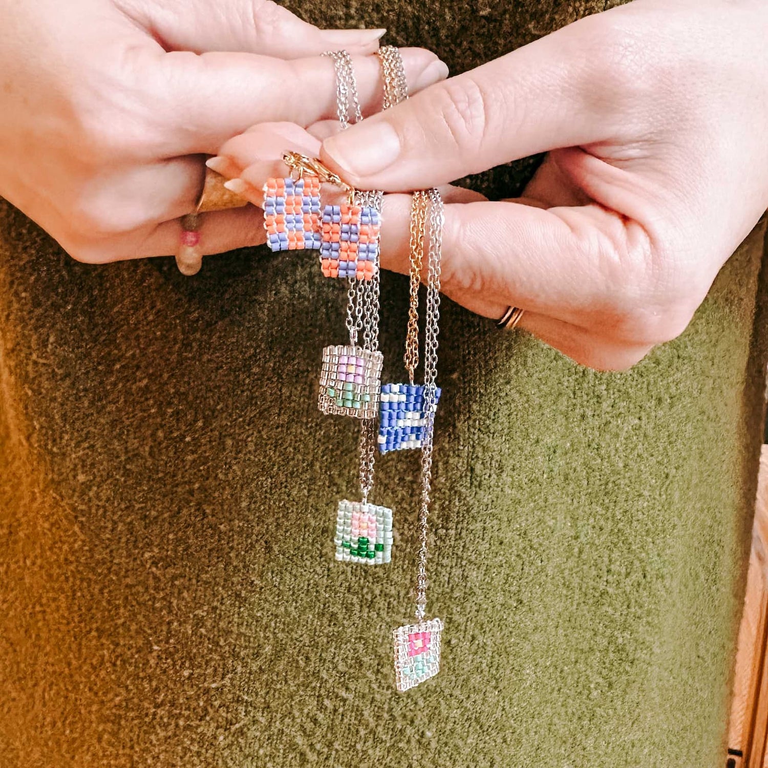 Hand hält mehrere fertige Ketten mit bunten Perlenanhängern beim Perlenschmuck Workshop von GRIMMS GARTEN, kreativer DIY Schmuckkurs in Berlin