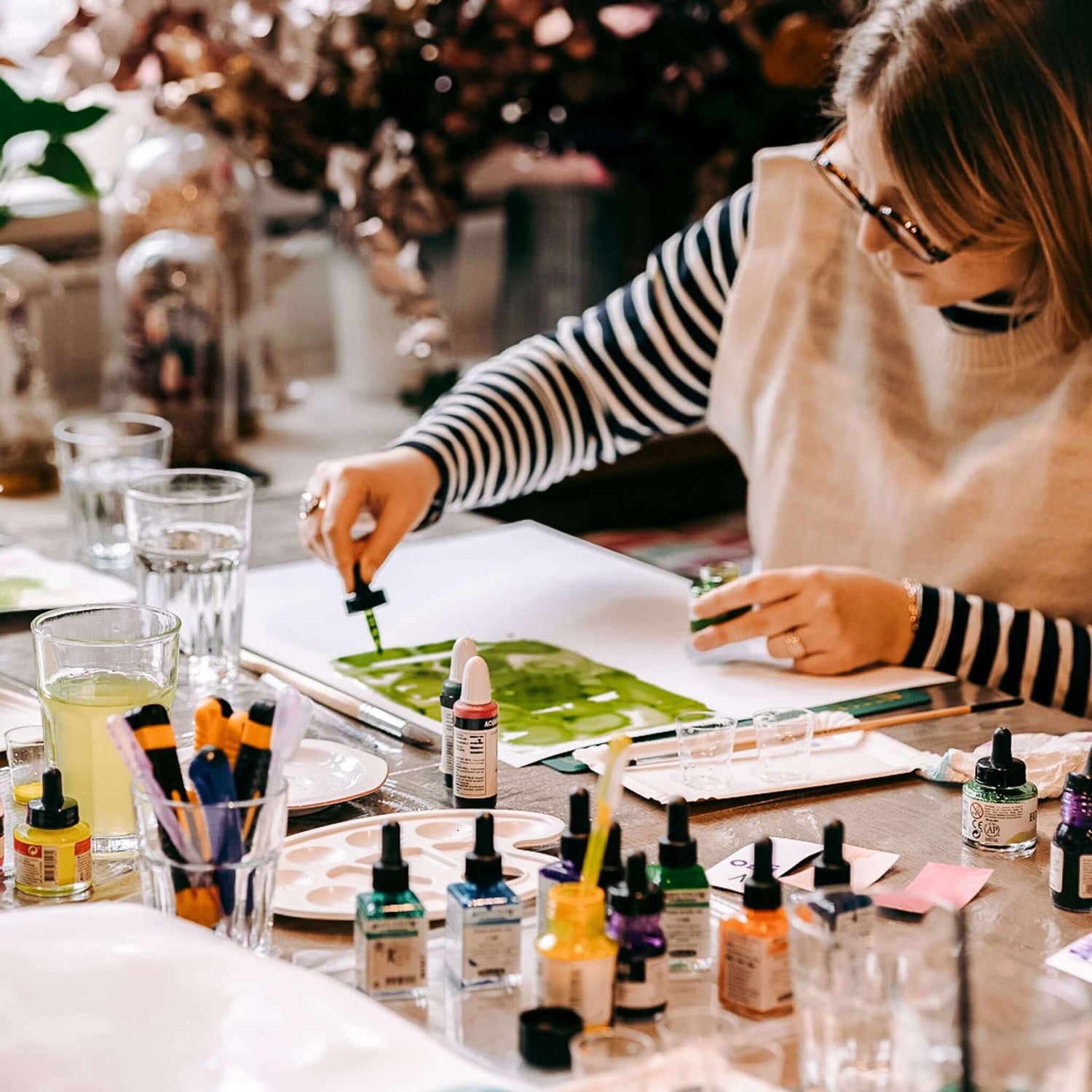 Teilnehmerin malt Aquarell Flower Bouquet am Tisch mit Pinseln und Farben – Workshop ohne Vorkenntnisse.