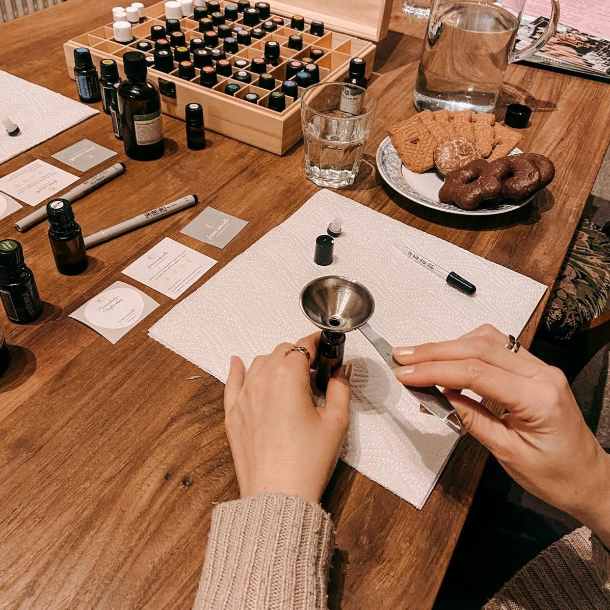 Trichter in kleiner Flasche mit ätherischen Ölen auf Tisch – naturparfum workshop, nachhaltige kosmetik, diy duftkurs, auch für Firmenevents.
