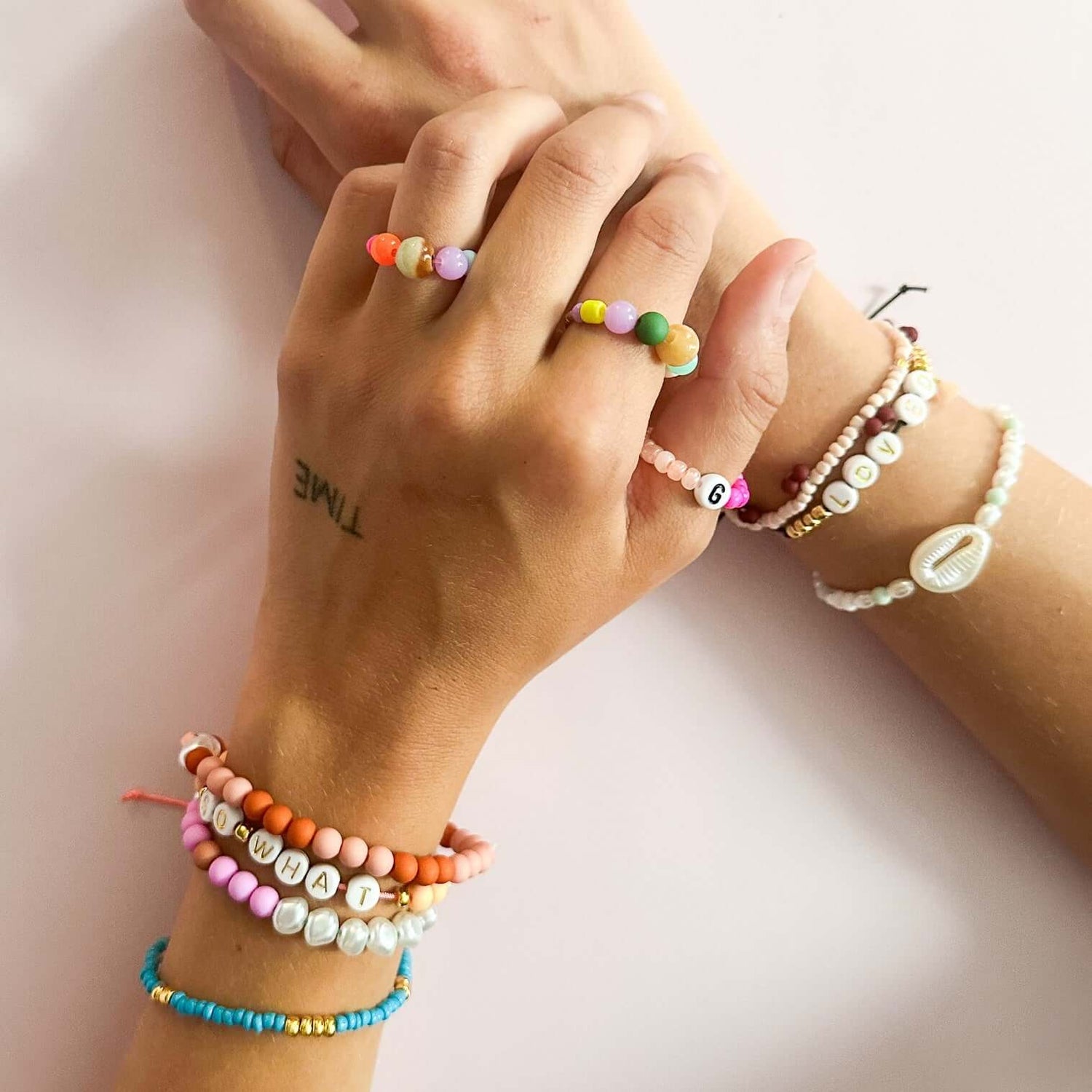 Zwei Hände mit vielen Perlenringen und Armbändern – DIY Perlenschmuck Workshop Berlin, Armband selbst machen.